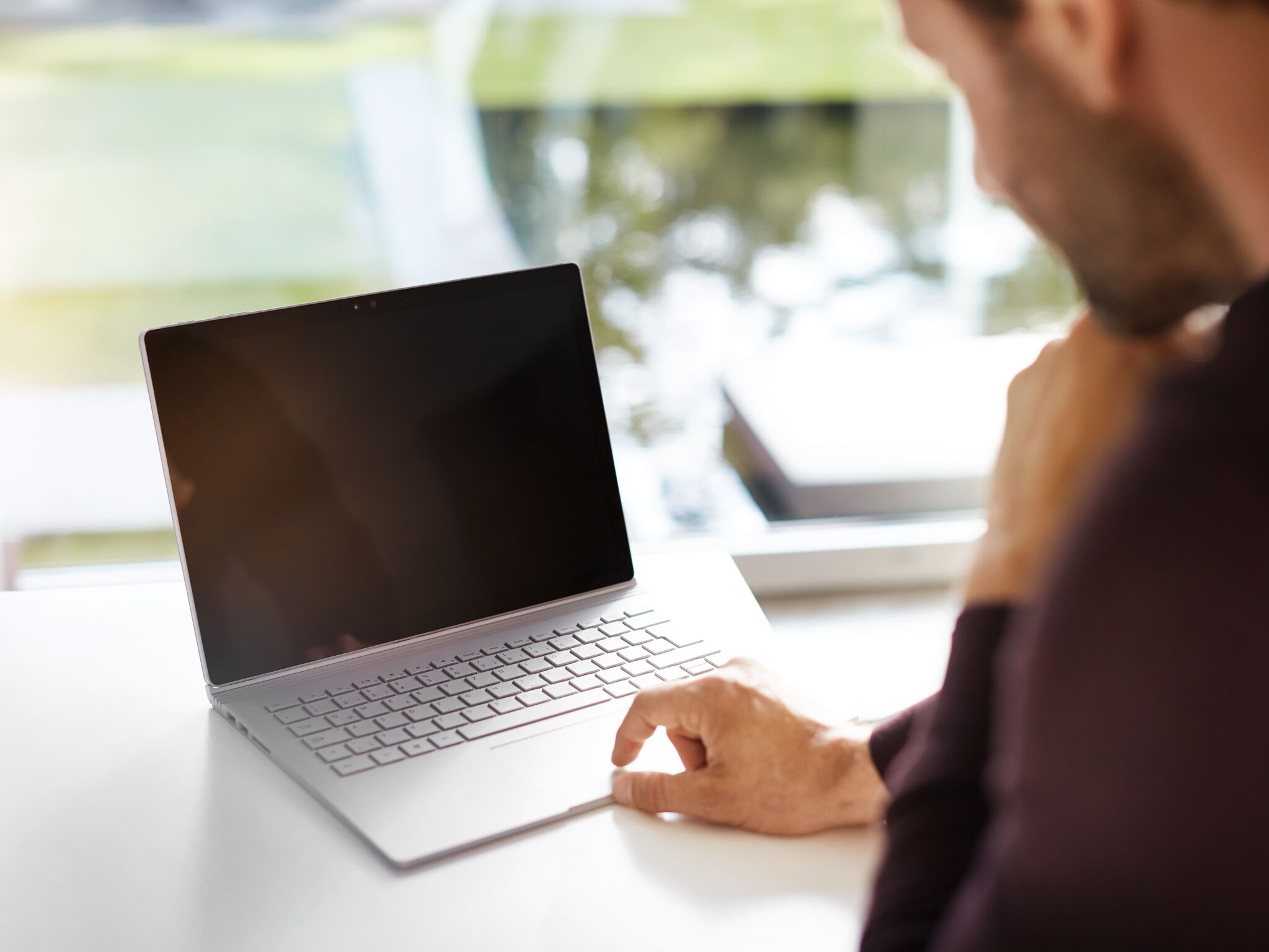 Ein Mann sitzt an einem Schreibtisch und guckt nachdenklich auf seinen Laptop.