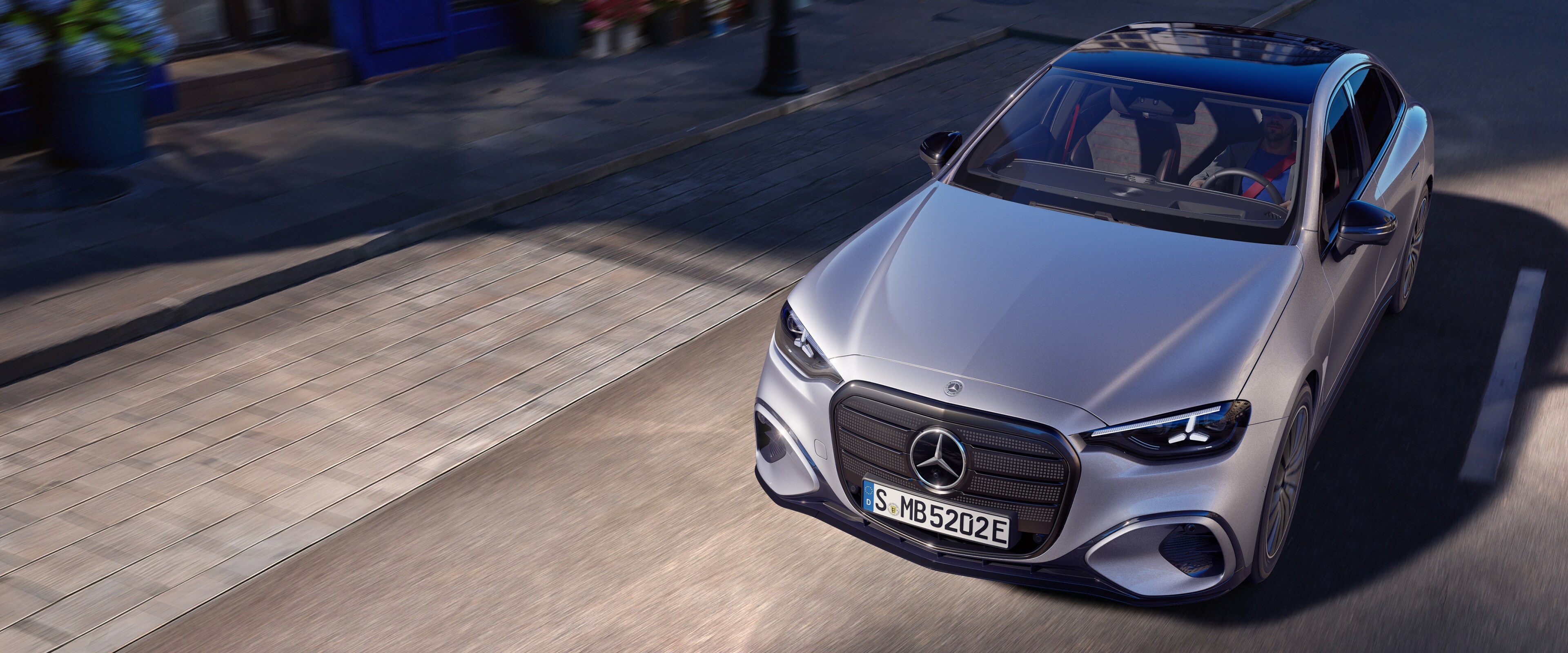 Die neue elektrische C-Klasse von Mercedes-Benz in Silber fährt auf einer Sztaße entlang.