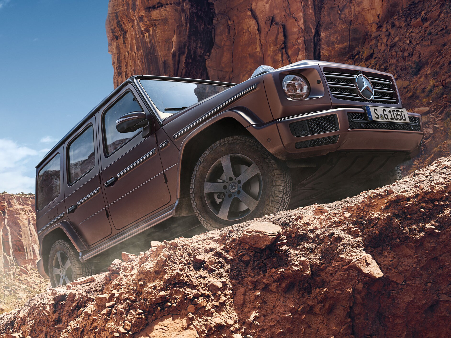 Seitenansicht der Mercedes-Benz G-Klasse in den Bergen einen steinigen Weg hochfahrend.