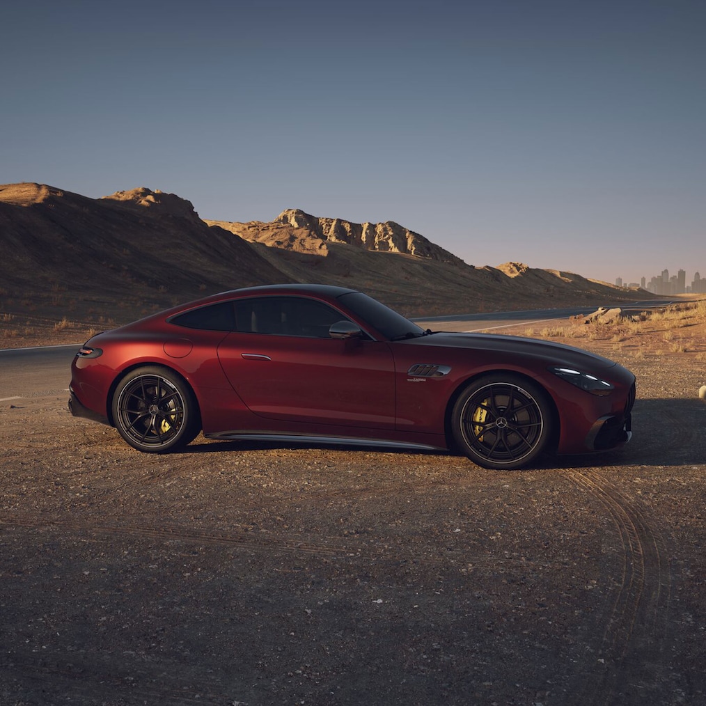 Seitenansicht eines roten Mercedes-AMG GT Coupés in einer Wüstenlandschaft parkend.