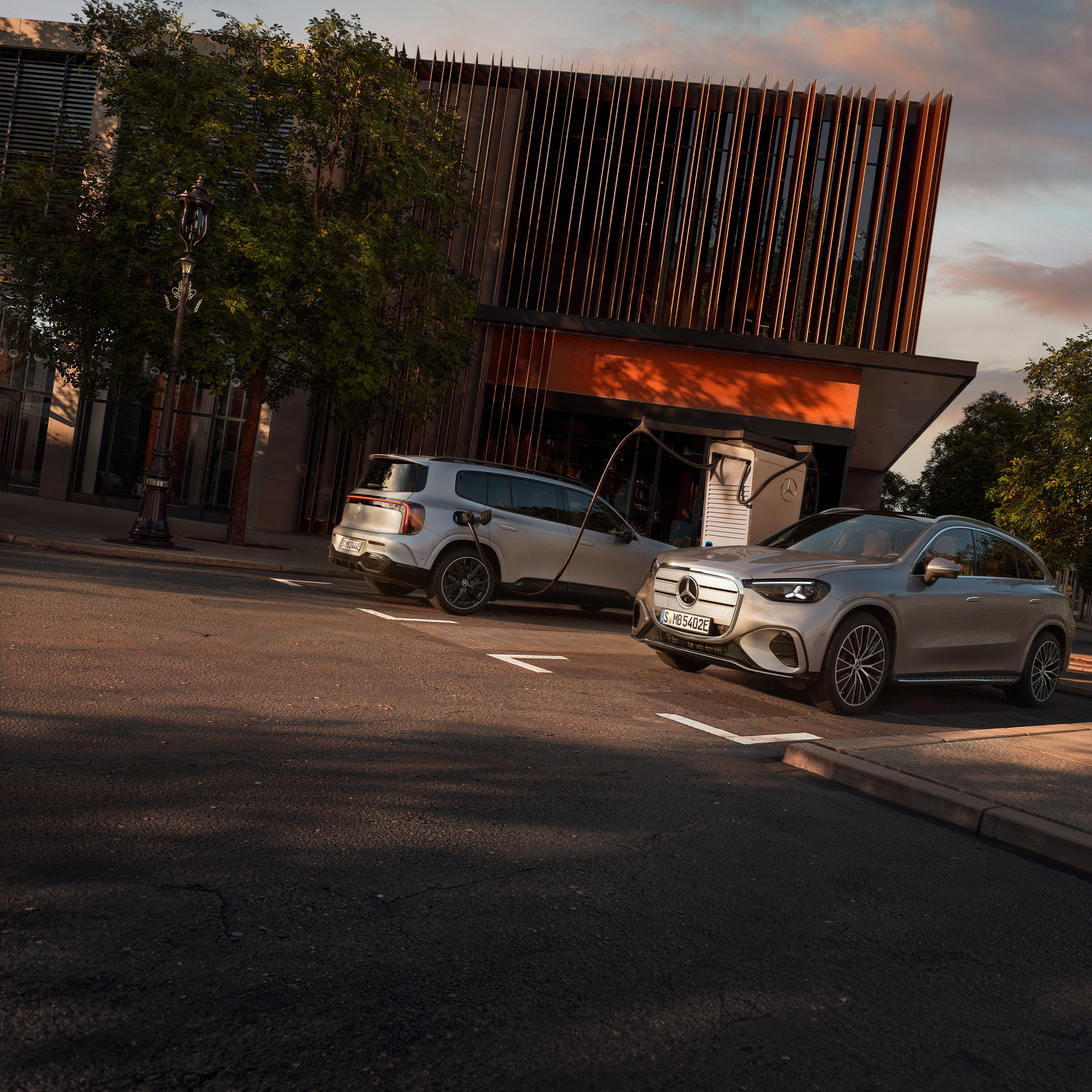 Elektrofahrzeuge | Mercedes-Benz Zwei Elektrofahrzeuge von Mercedes-Benz stehen auf einem Parkplatz und werden geladen.