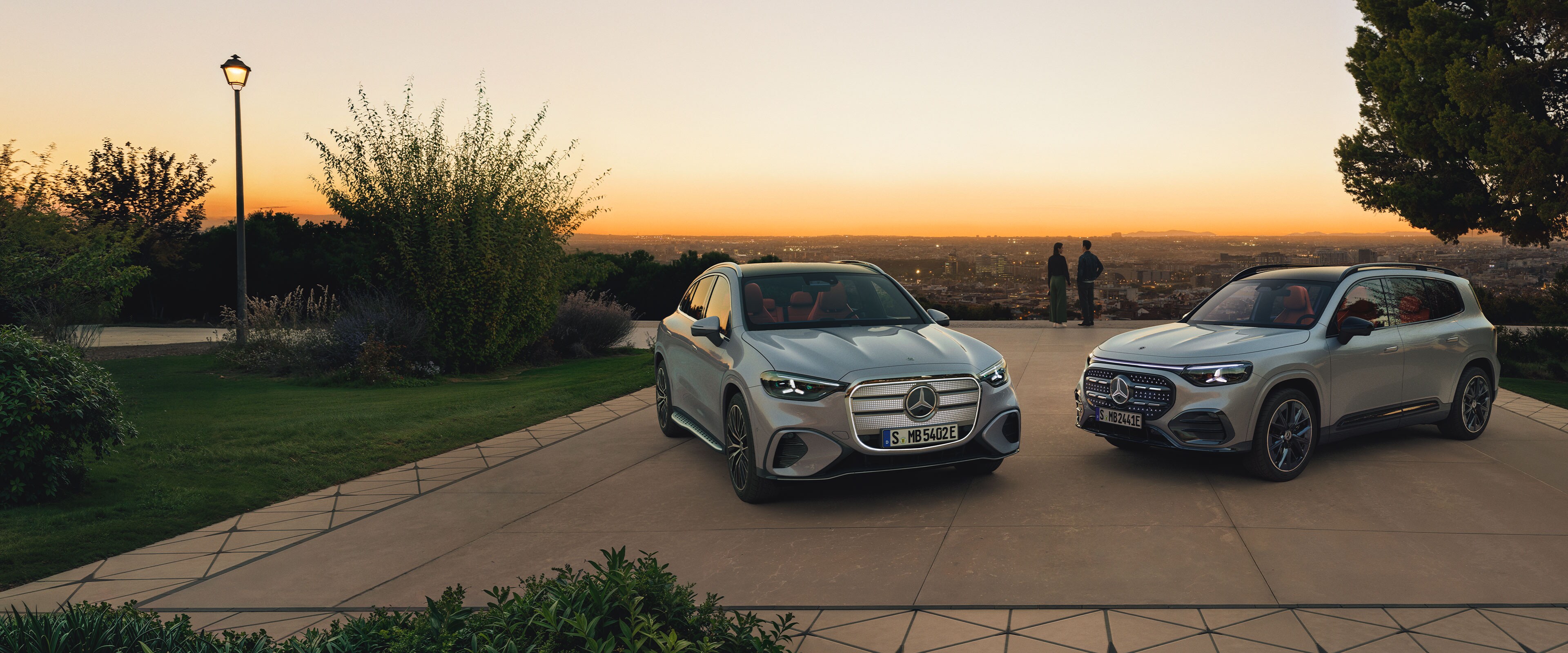 Zwei SUV-Modelle von Mercedes-Benz die schräg zu einander auf einem Parkplatz stehen.