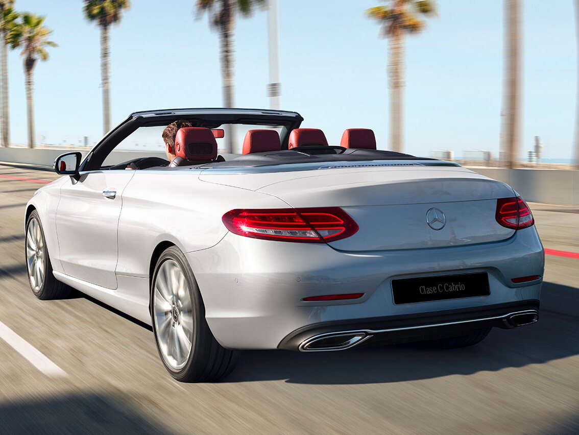 Ein weißes C-Klasse Cabriolet auf einer von Palmen gesäumten Straße.