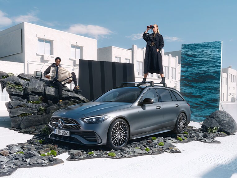 Das Mercedes-Benz C-Klasse T-Modell in einer seitlichen Frontansicht vor einer weißen Gebäudelandschaft.
