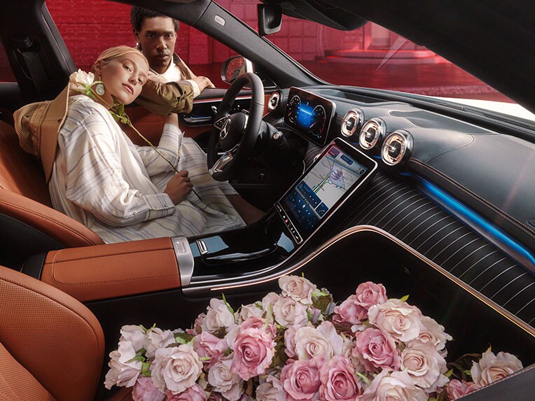 Eine Frau am Steuer des Mercedes-Benz C-Klasse T-Modells in dem Blumen auf dem Beifahrersitz liegen.