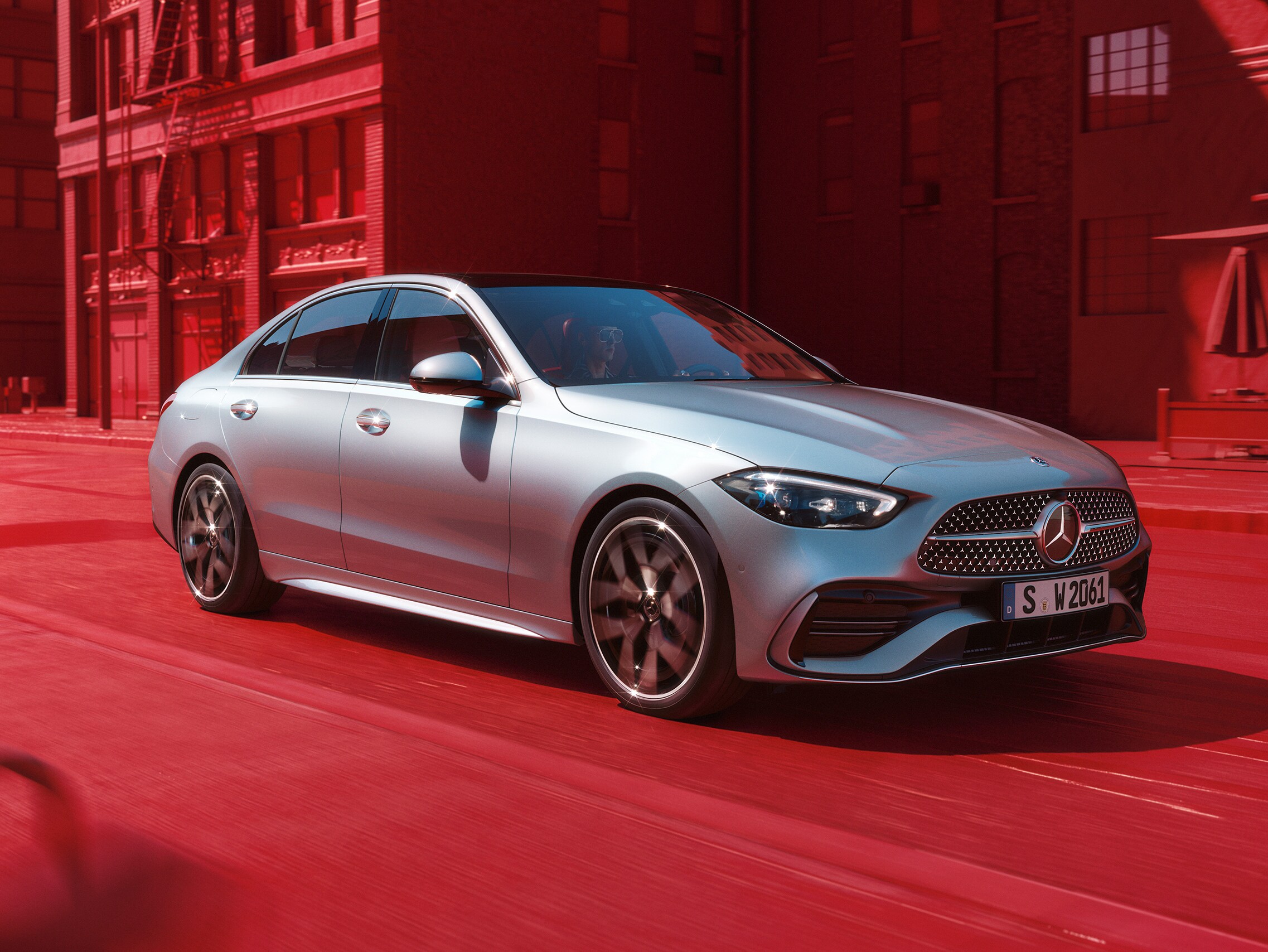 Eine silberne C-Klasse von Mercedes-Benz vor einer roten Stadtkulisse.