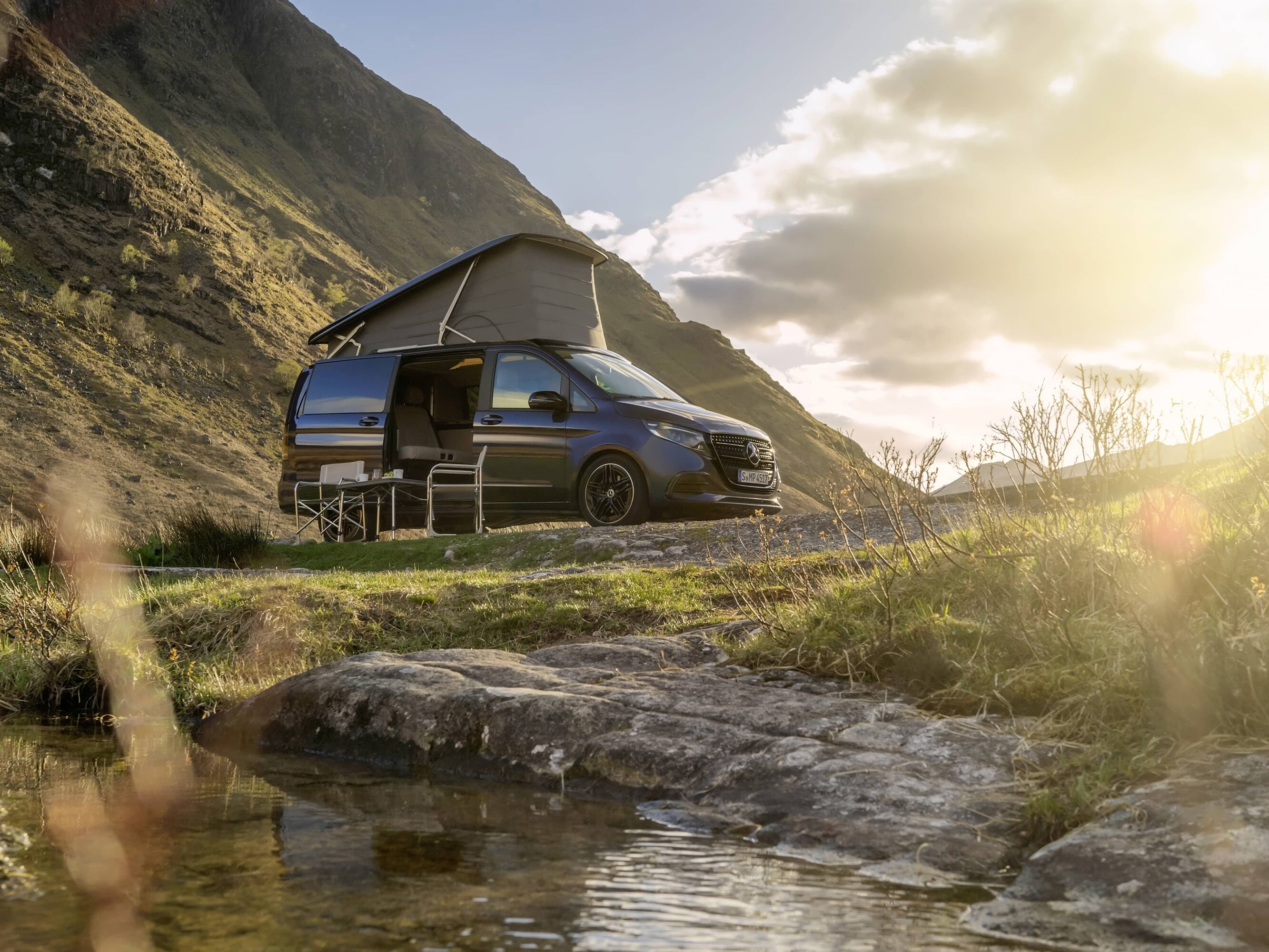 Ein Mercedes-Benz Marco Polo-Wohnmobil mit Aufstelldach inmitten einer malerischen Berglandschaft.