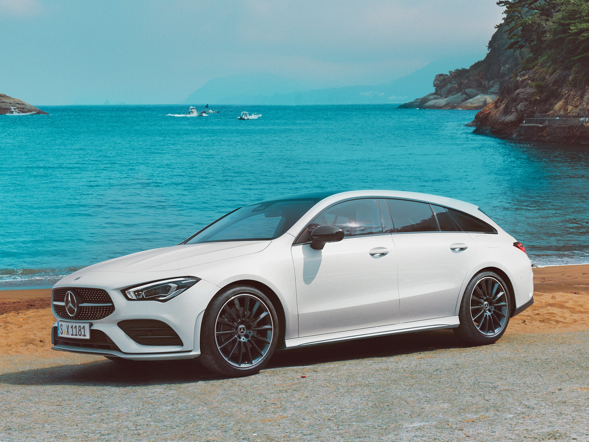 Ein weißer CLA Shooting Brake auf einer Straße am Meer.