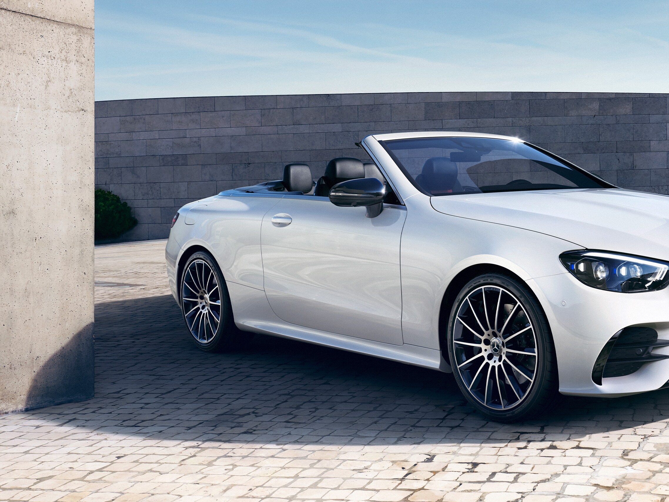 Ein silbernes E-Klasse Cabriolet steht auf Kopfsteinpflaster.