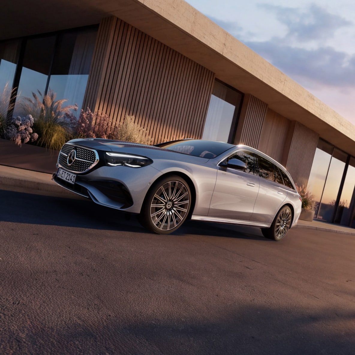 Ein silbernes Mercedes-Benz E-Klasse T-Modell steht neben einem Haus und wird von der Abendsonne angestrahlt.