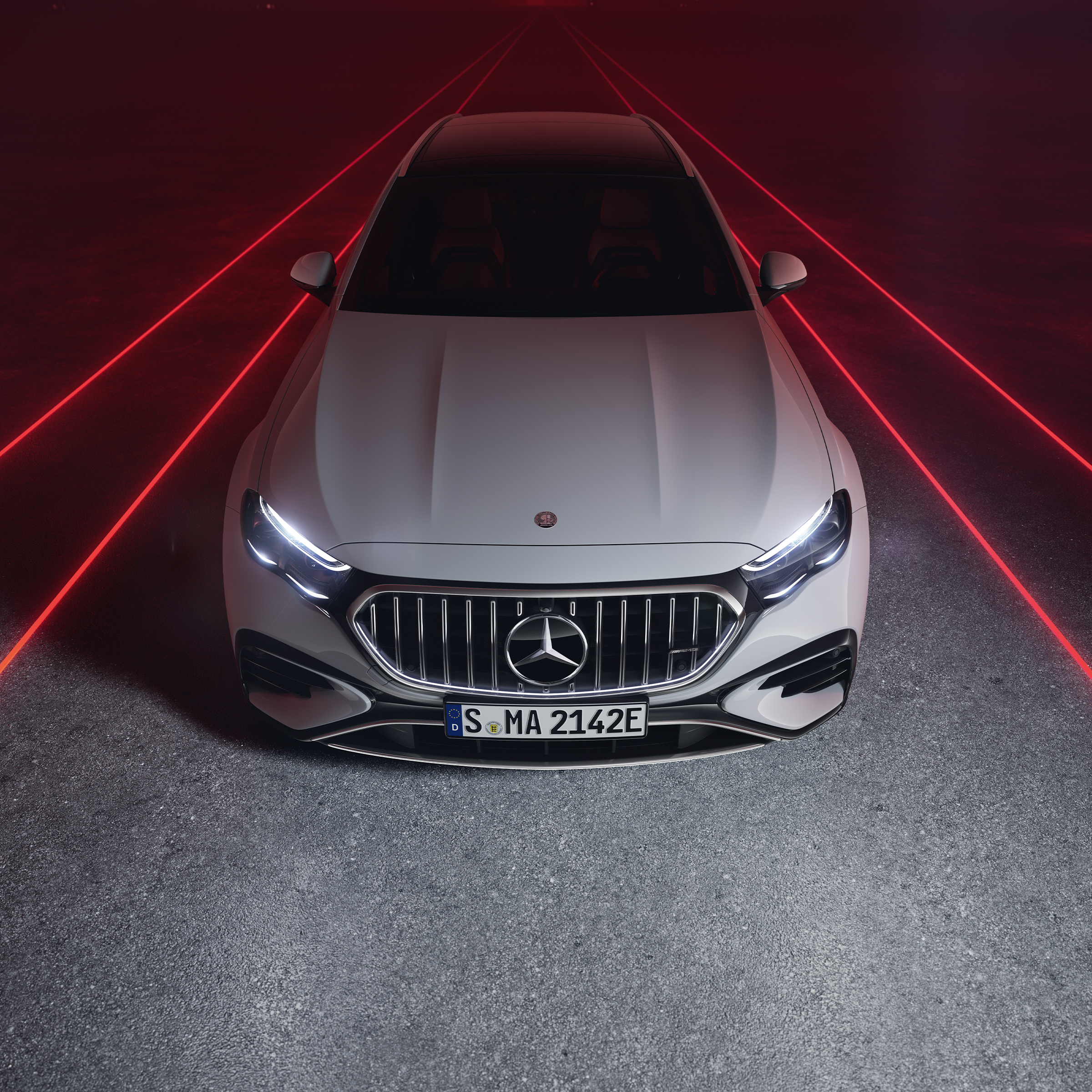 Mercedes-AMG E 53 HYBRID 4MATIC+ in einer Frontansicht vor rotem Hintergrund, von oben gesehen.