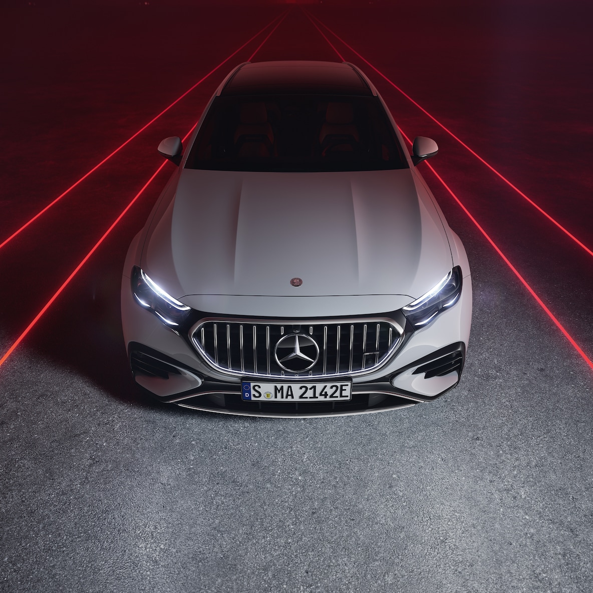Mercedes-AMG E 53 HYBRID 4MATIC+ in einer Frontansicht vor rotem Hintergrund, von oben gesehen.