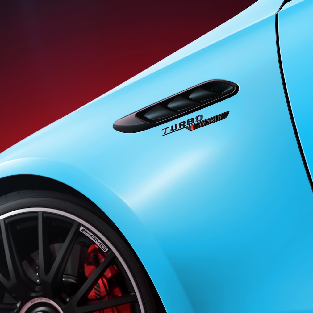 Nahaufnahme eines türkisblauen Mercedes-AMG mit „Turbo Hybrid“-Schriftzug am Kotflügel und sichtbarem Teil des schwarzen Leichtmetallrads.