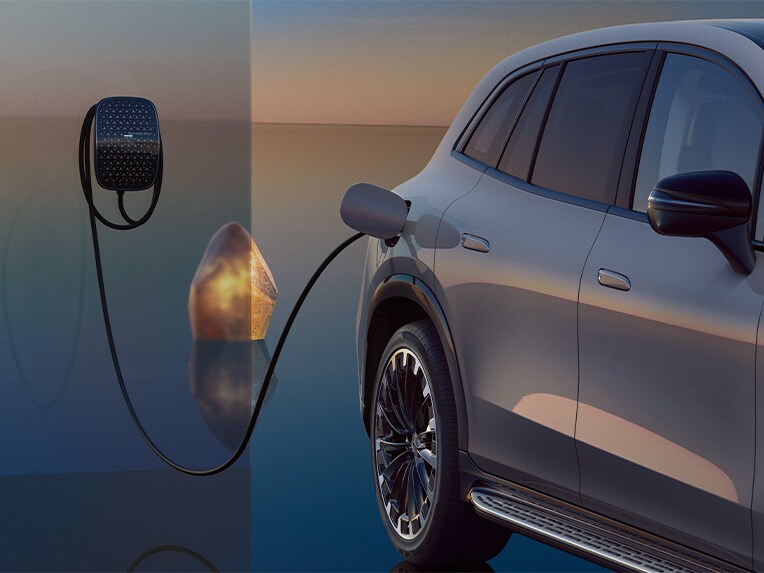 Der EQS SUV in Seitenansicht während eines Ladevorgangs, verbunden mit einer Mercedes-Benz Wallbox.