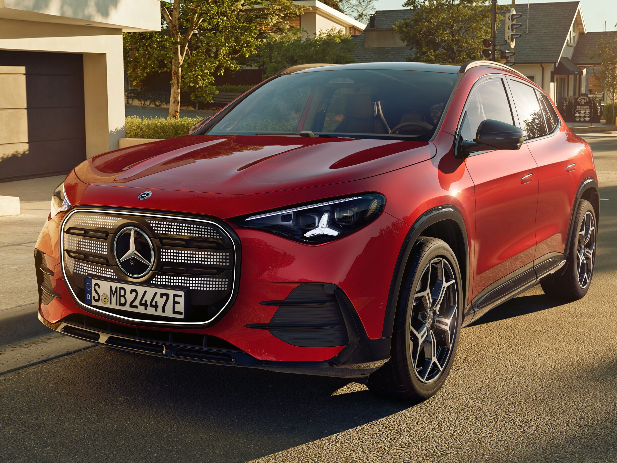 Der neue elektrische GLA in Rot in seitlicher Frontalansicht steht auf einer Straße in einer Wohnsiedlung.
