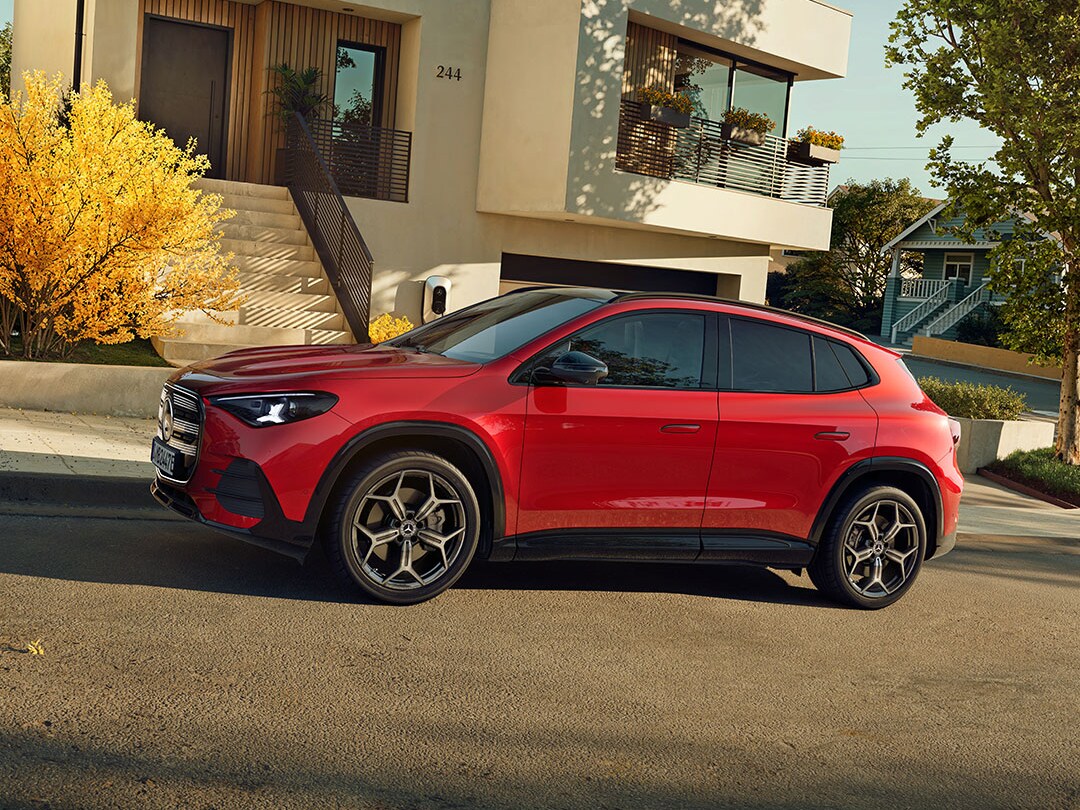 Der neue elektrische GLA in Rot in seitlicher Frontalansicht steht auf einer Straße in einer Wohnsiedlung.