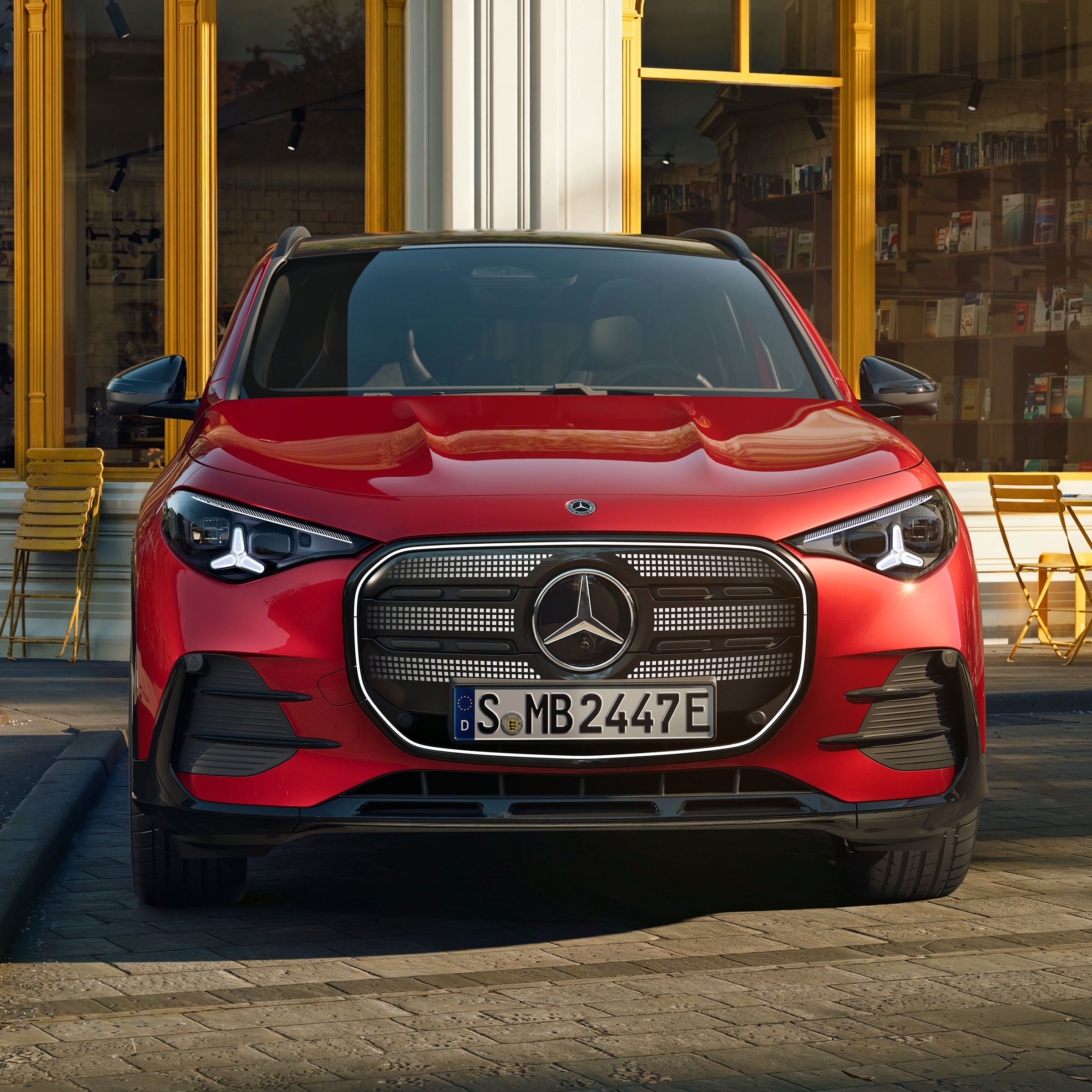 Fahrzeug-Angebote | Mercedes-Benz. Der neue elektrische GLA in Rot in Frontalansicht steht auf einer Straße in einer Wohnsiedlung.