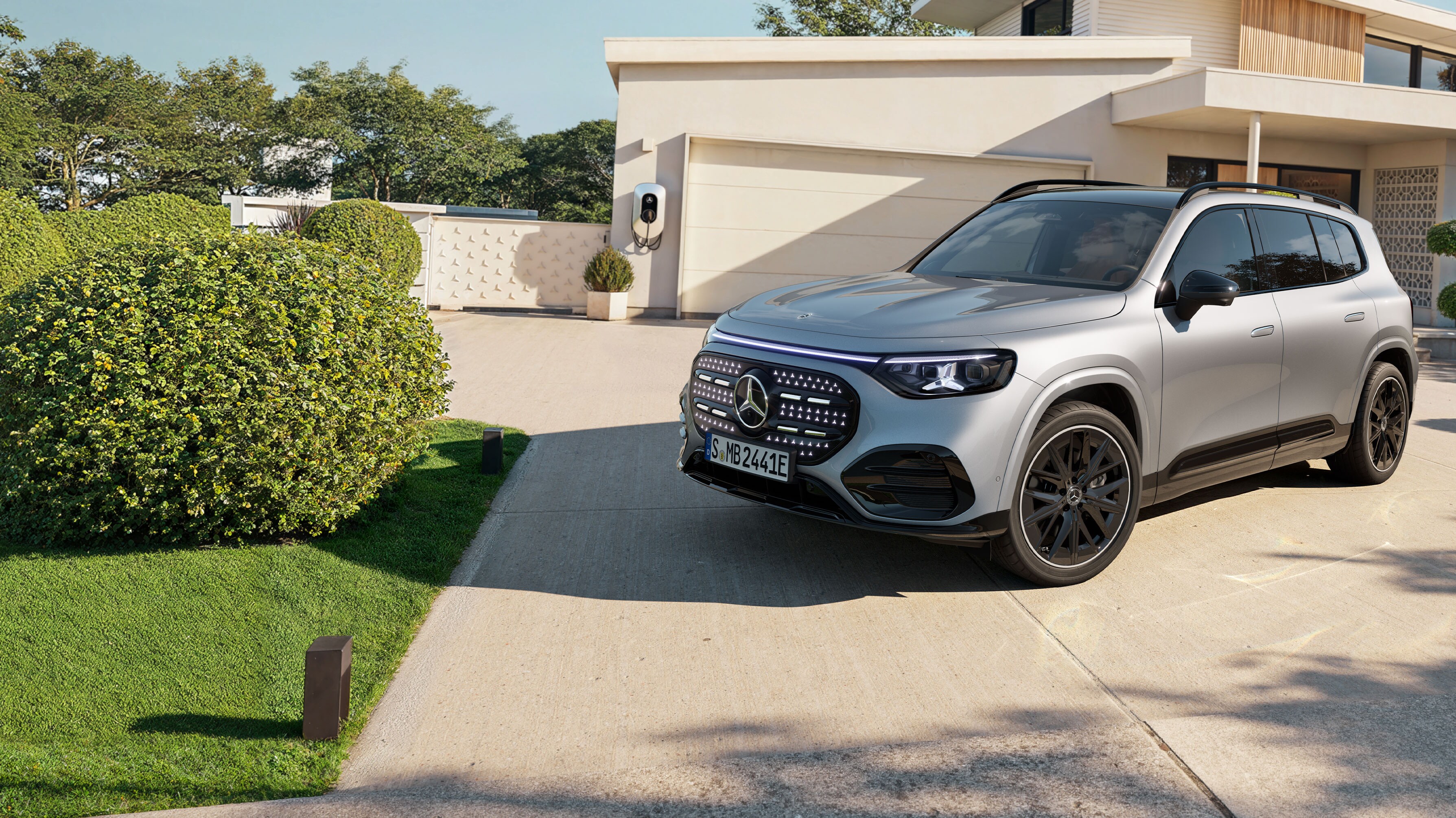 Ein vollelektrischer GLB mit beleuchteten Kühlergrill steht auf einer Ausfahrt.