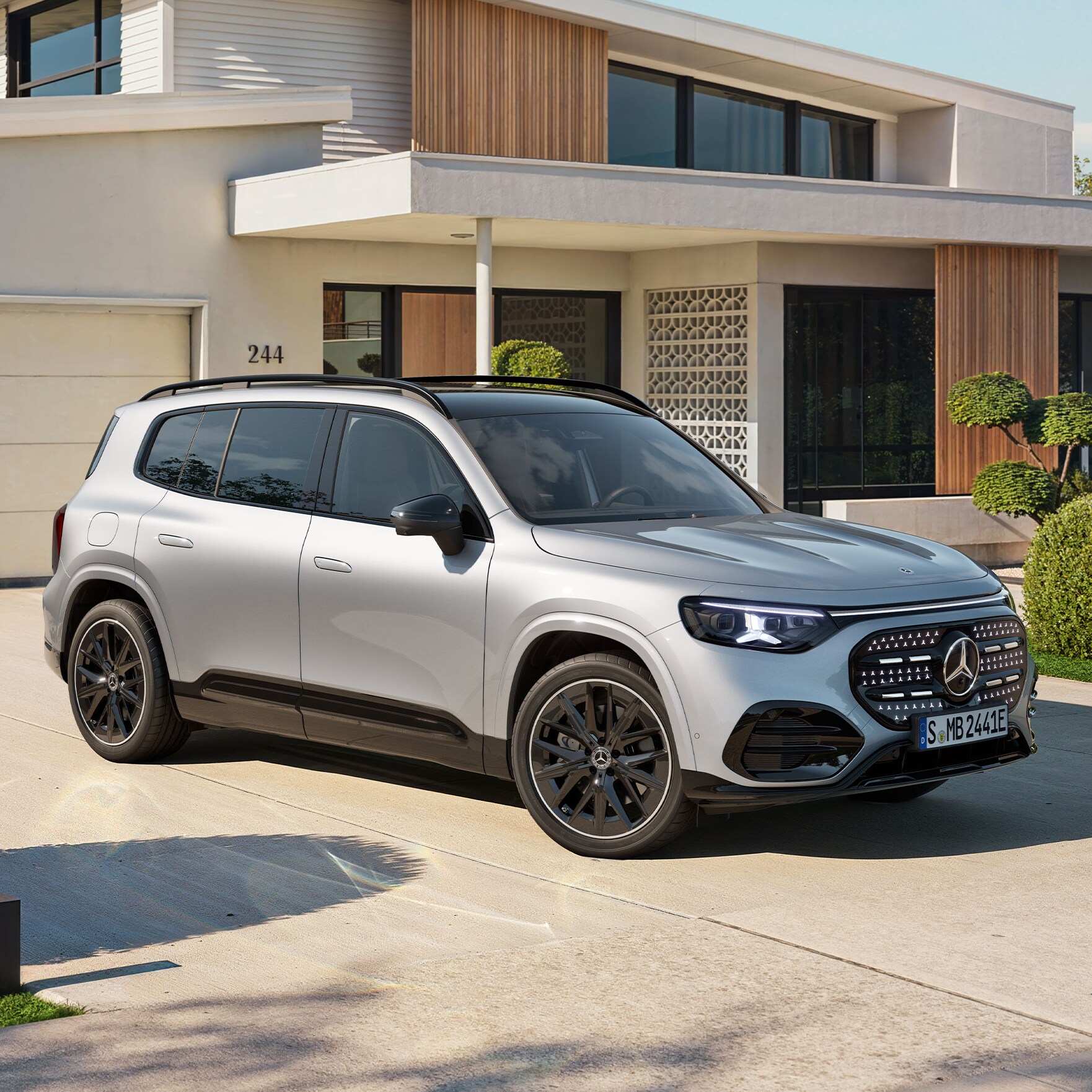 Ein vollelektrischer GLB SUV mit beleuchteten Kühlergrill steht auf einer Ausfahrt.