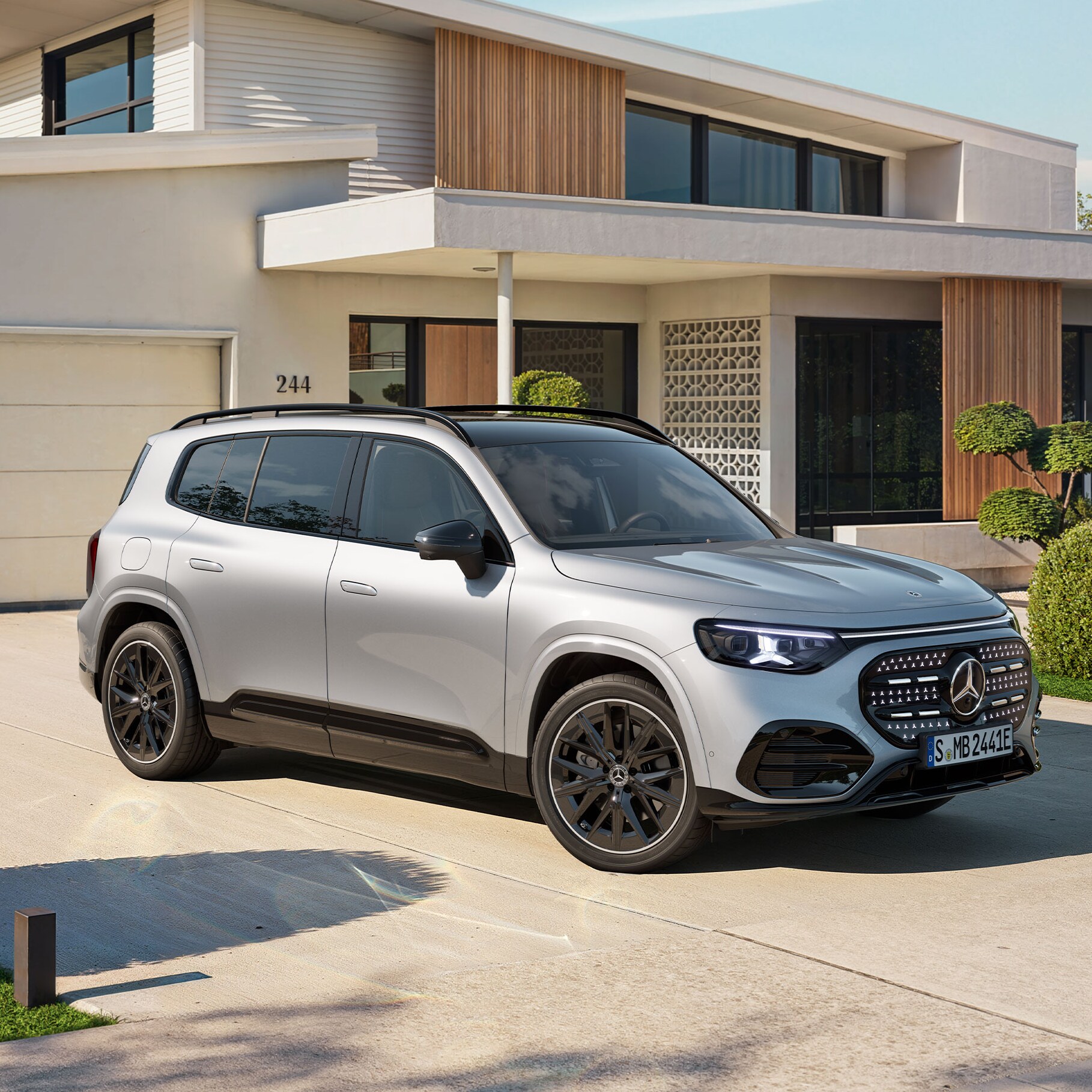 Ein vollelektrischer GLB SUV mit beleuchteten Kühlergrill steht auf einer Ausfahrt.