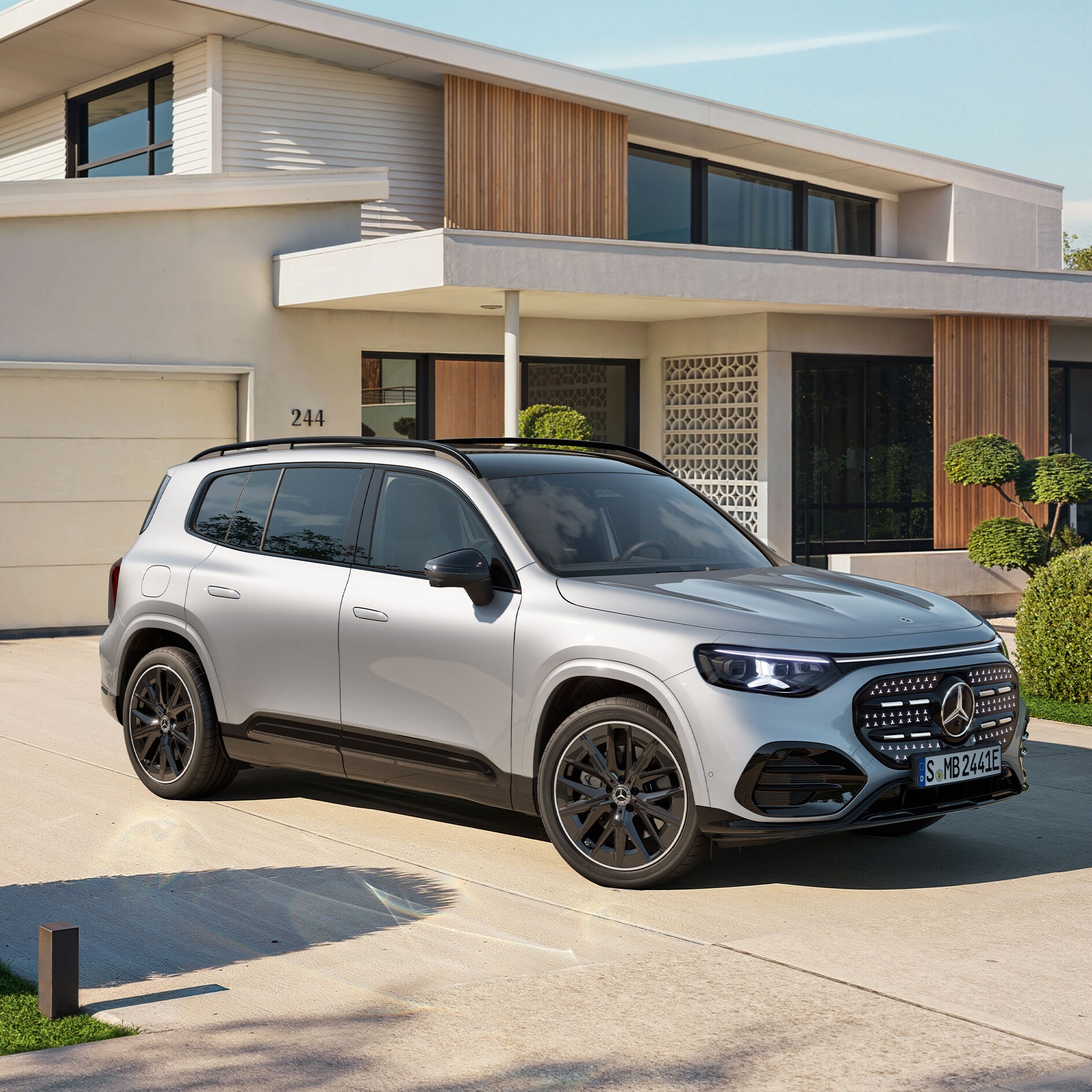 Ein vollelektrischer GLB SUV mit beleuchteten Kühlergrill steht auf einer Ausfahrt.