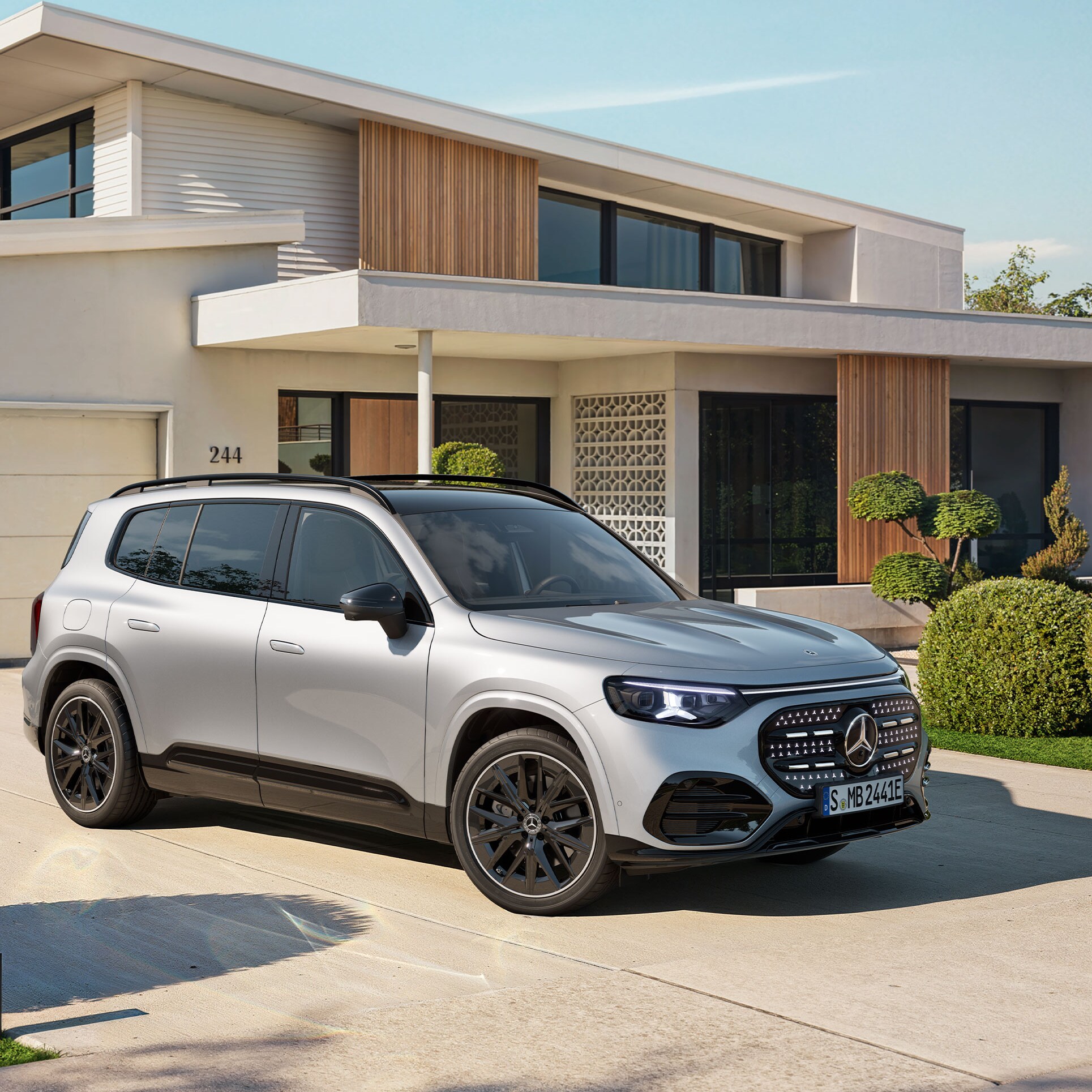 Ein vollelektrischer GLB SUV mit beleuchteten Kühlergrill steht auf einer Ausfahrt.