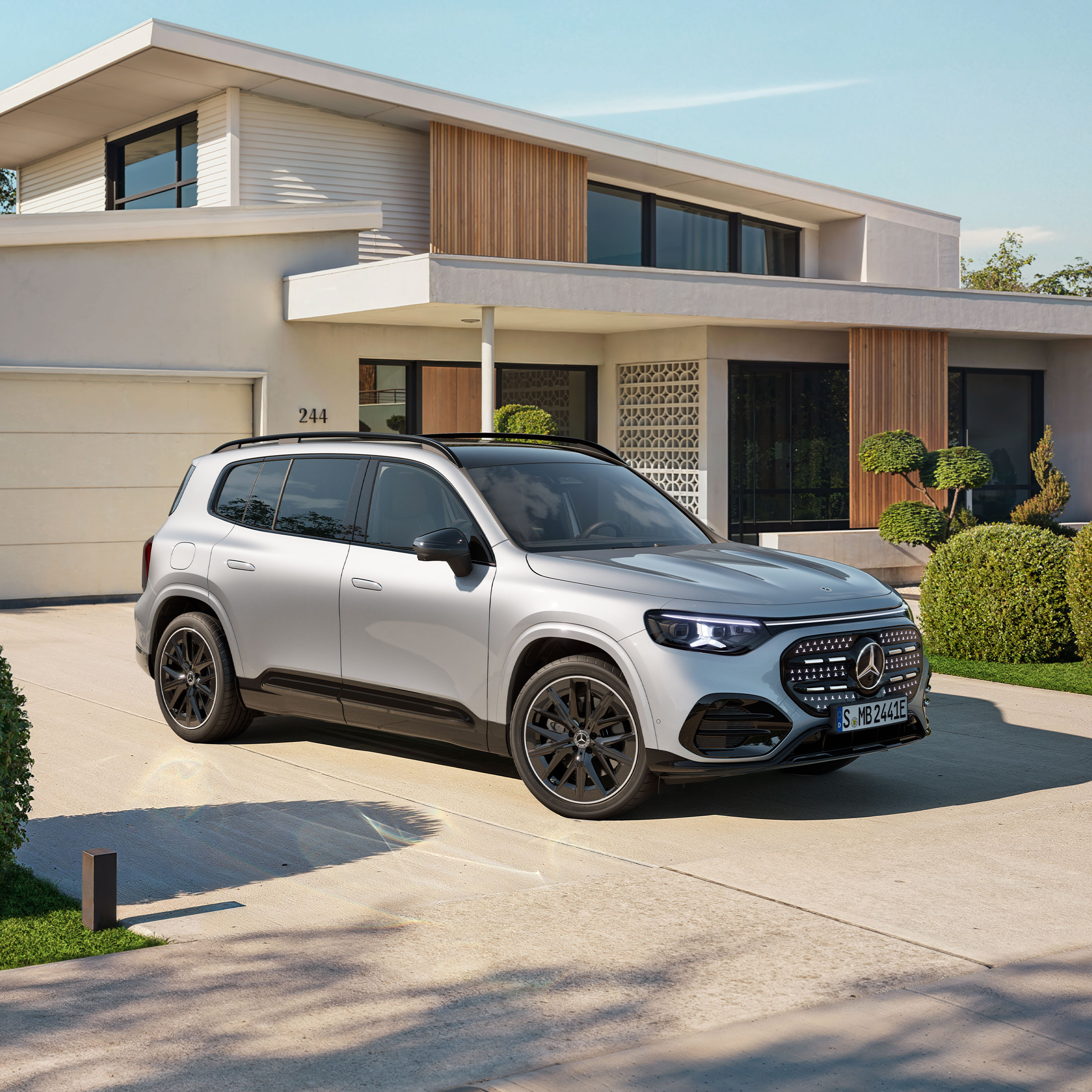 Ein vollelektrischer GLB SUV mit beleuchteten Kühlergrill steht auf einer Ausfahrt.