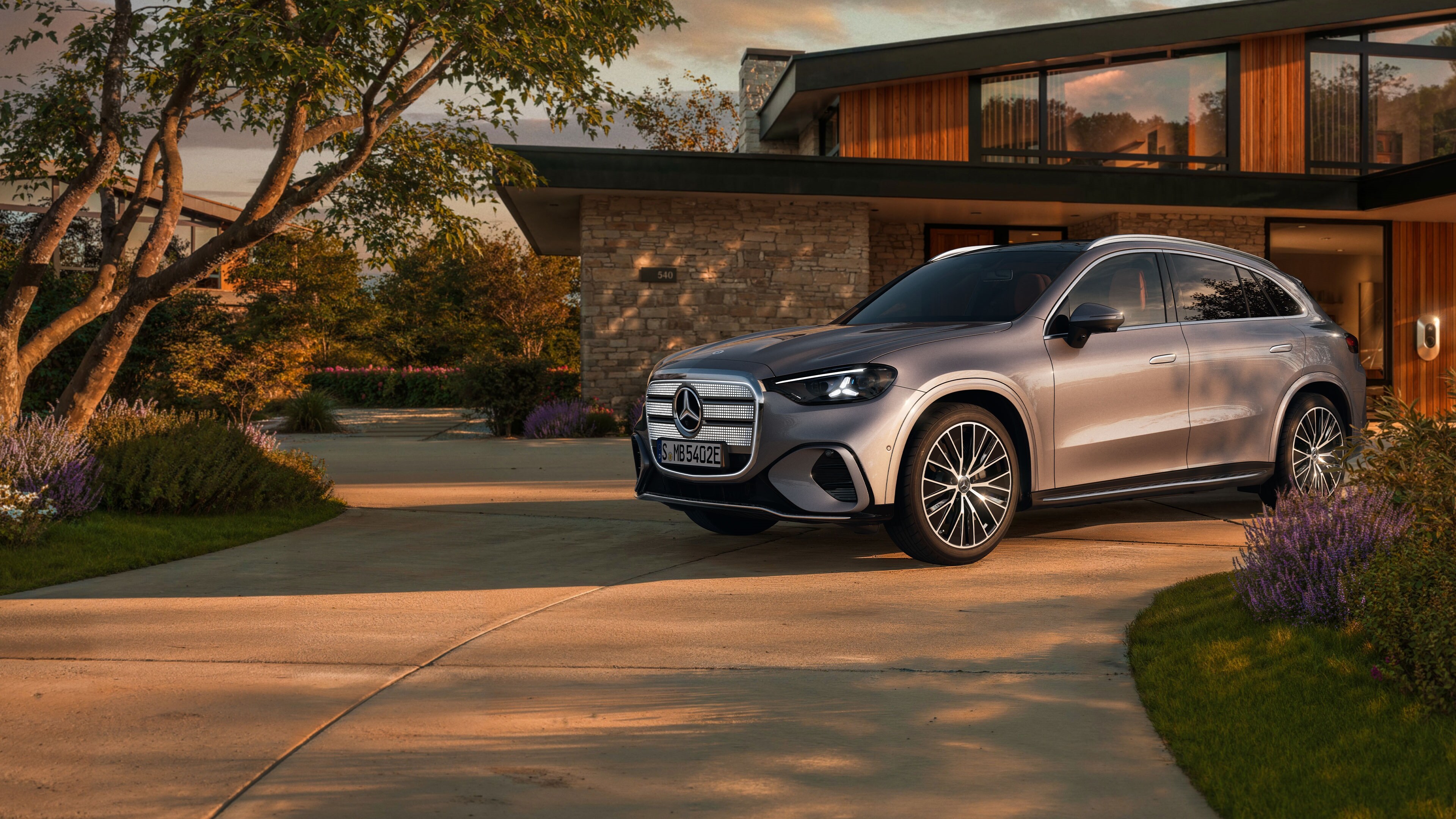 Ein vollelektrischer GLC SUV mit beleuchteten Kühlergrill steht auf einer Ausfahrt.