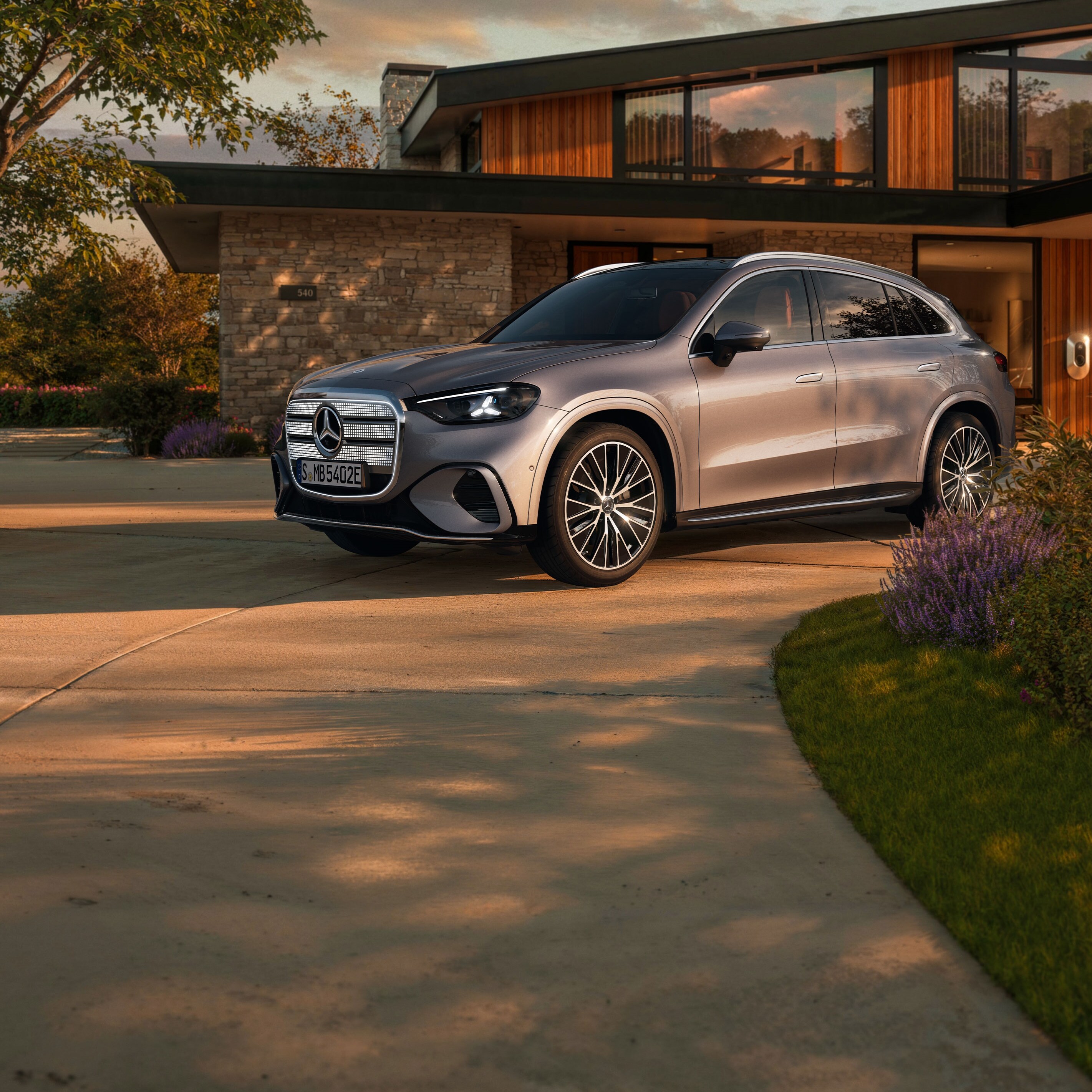 Ein vollelektrischer GLC SUV mit beleuchteten Kühlergrill steht auf einer Ausfahrt.