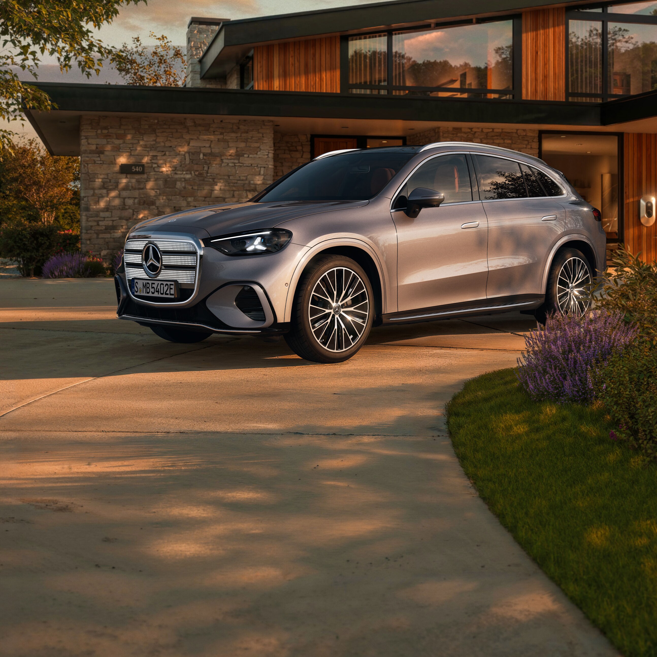 Ein vollelektrischer GLC SUV mit beleuchteten Kühlergrill steht auf einer Ausfahrt.