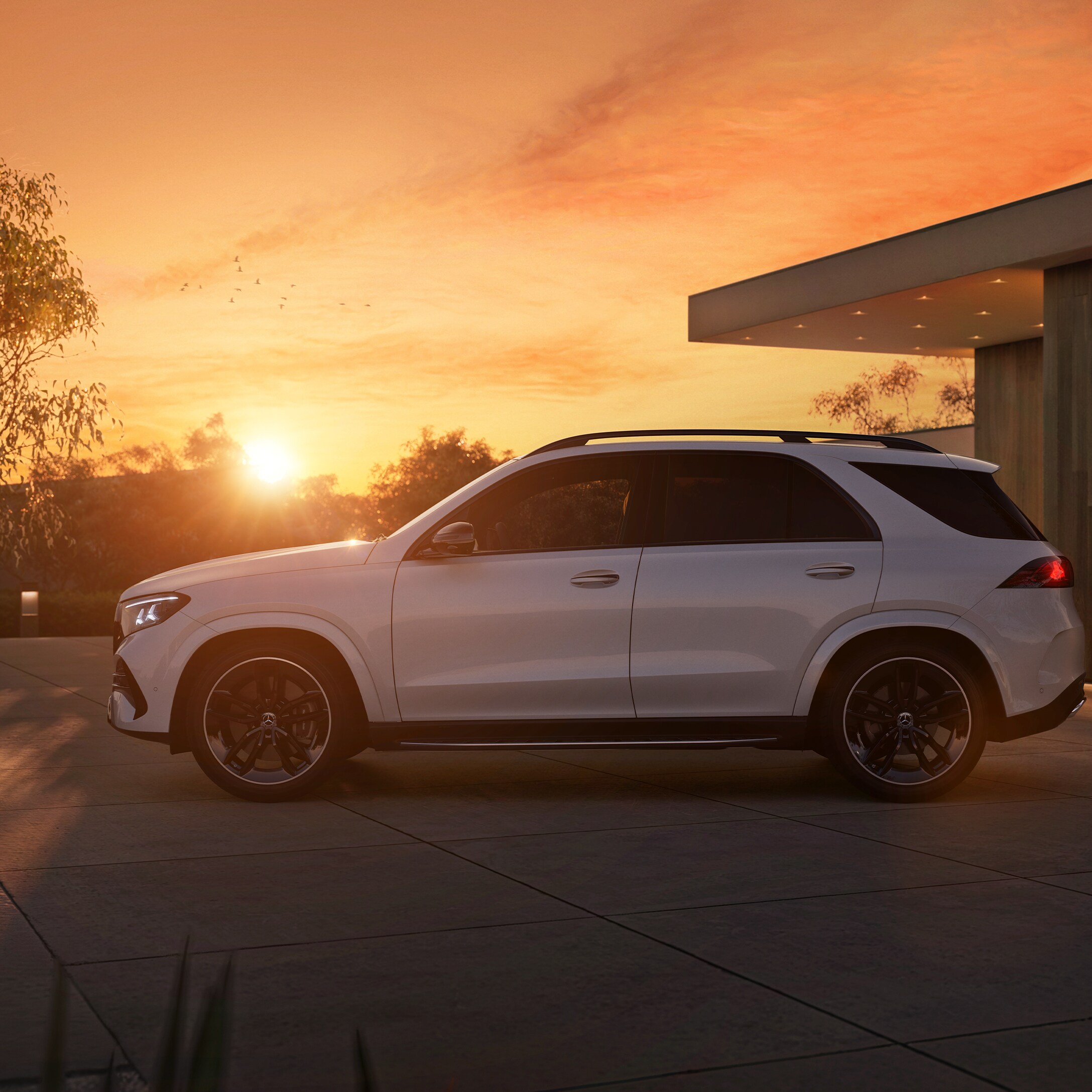 Die neue Mercedes-Benz GLE SUV, seitlicher Frontansicht parkend vor einem Haus bei Sonnenuntergang