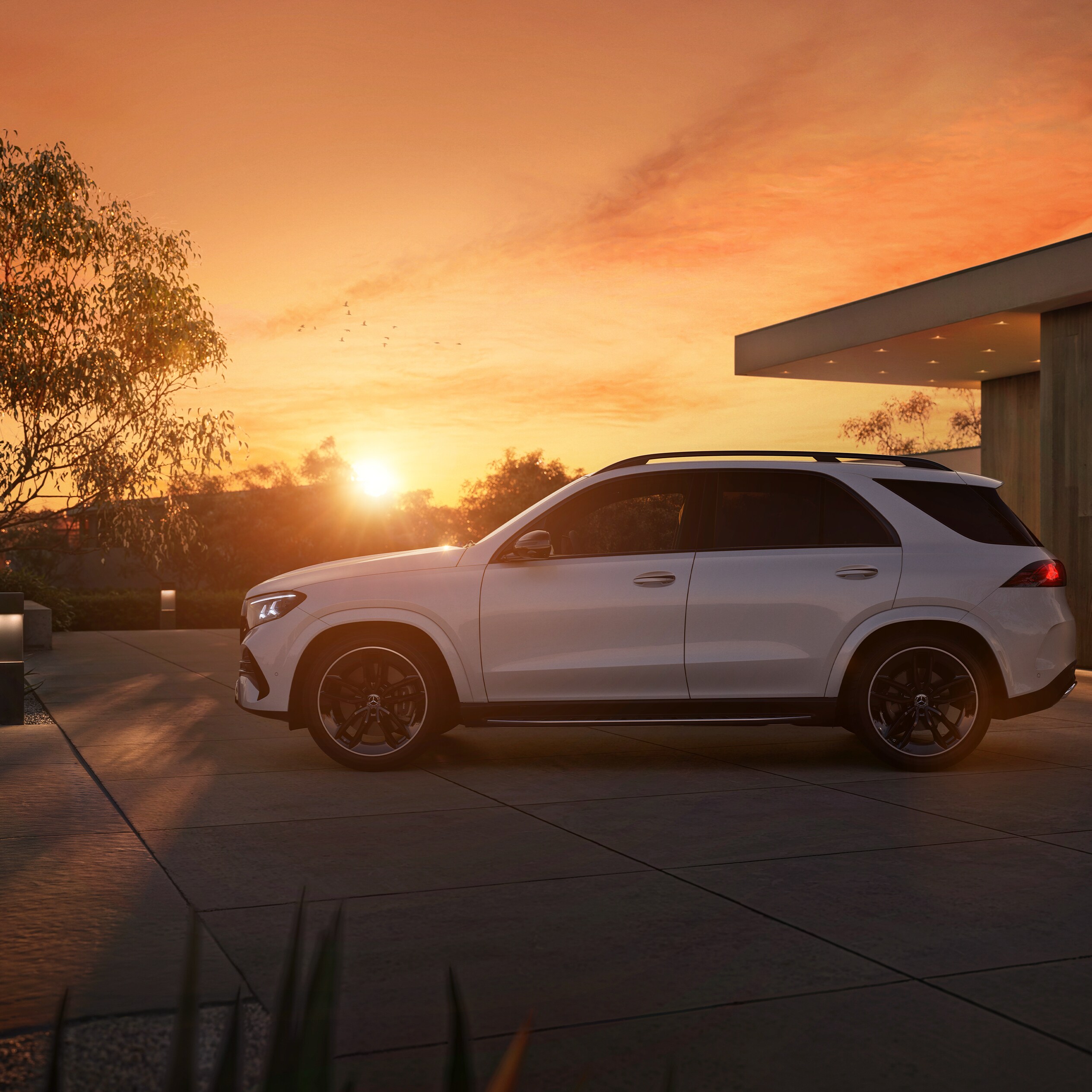 Der neue Mercedes-Benz GLE SUV, seitlicher Frontansicht parkend vor einem Haus bei Sonnenuntergang
