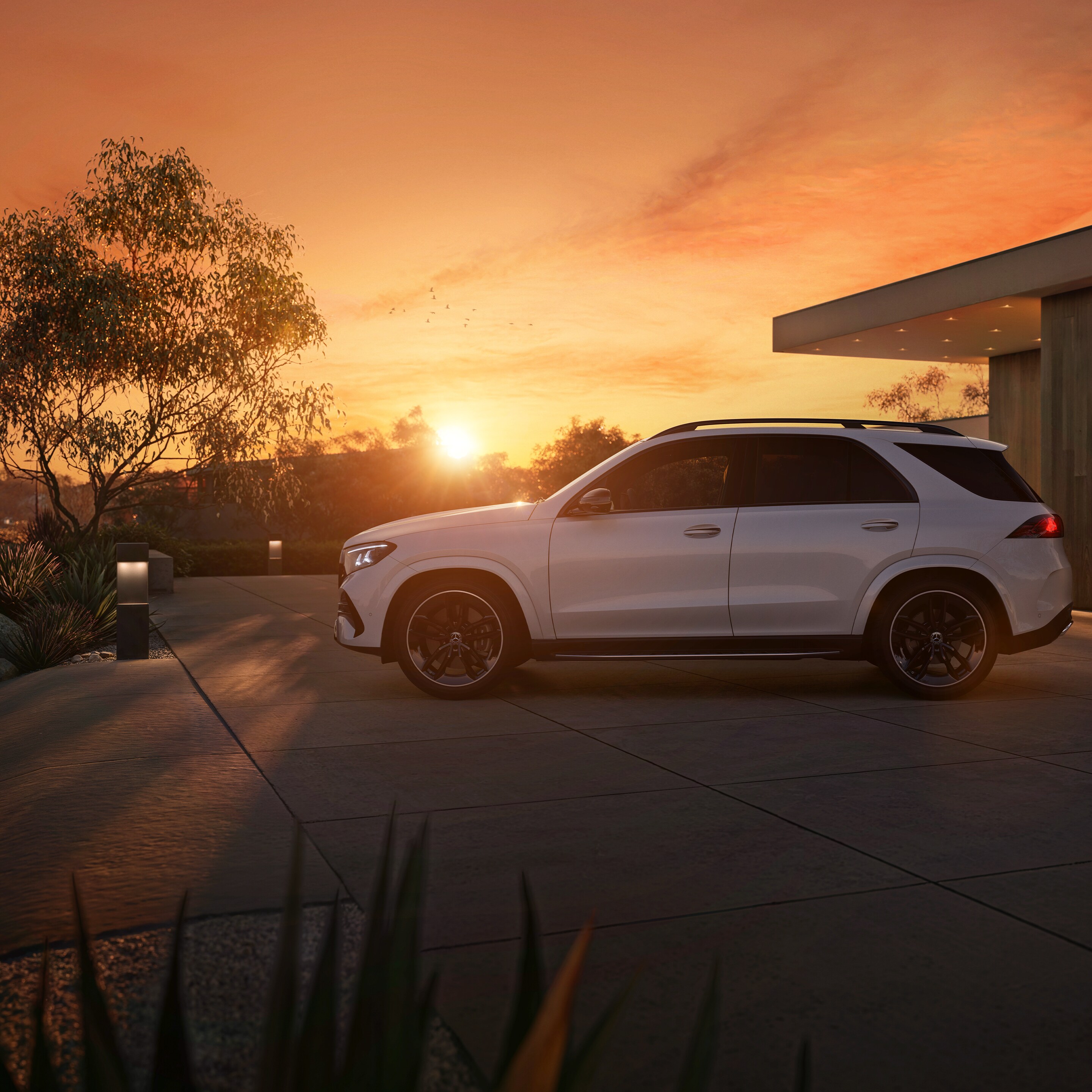 Der neue Mercedes-Benz GLE SUV, seitlicher Frontansicht parkend vor einem Haus bei Sonnenuntergang