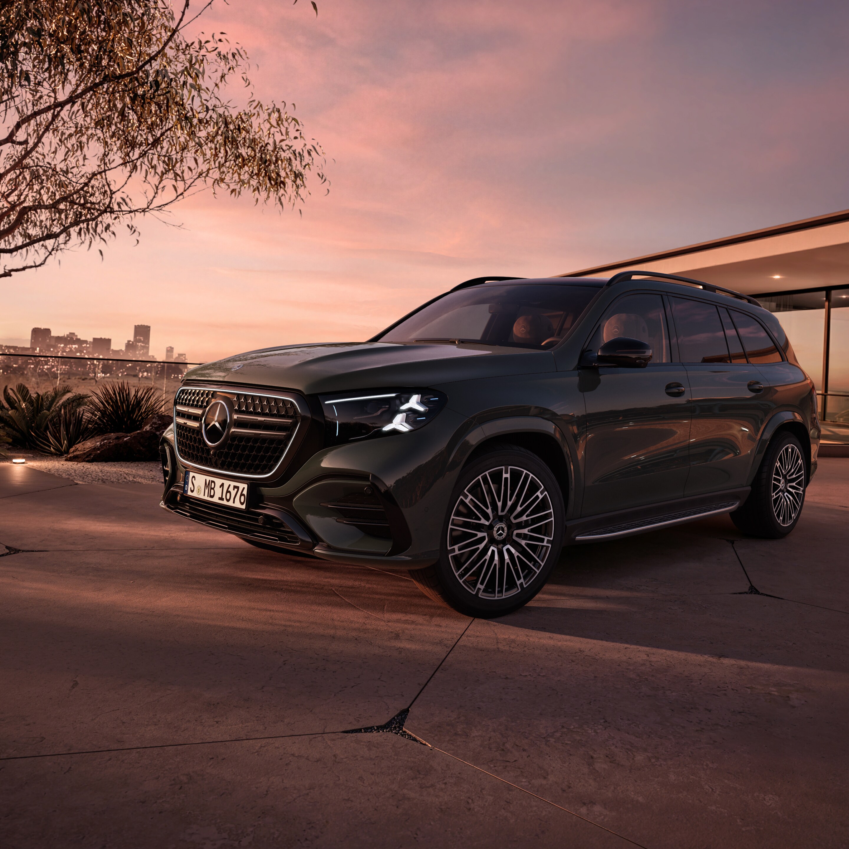 Dier neue Mercedes-Benz GLS, in seitlicher Frontansicht parkend vor einem Haus bei Sonnenuntergang.