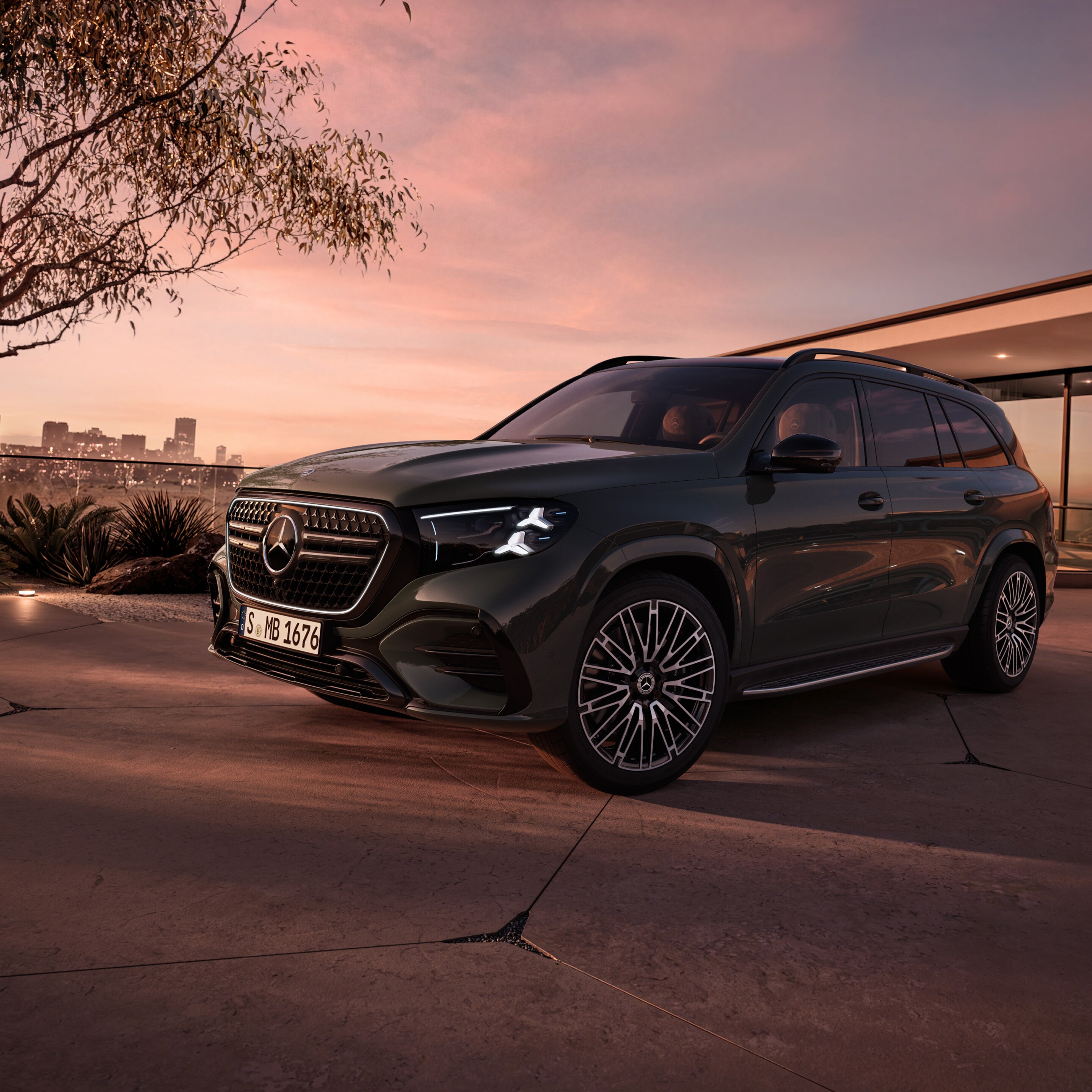 Dier neue Mercedes-Benz GLS, in seitlicher Frontansicht parkend vor einem Haus bei Sonnenuntergang.