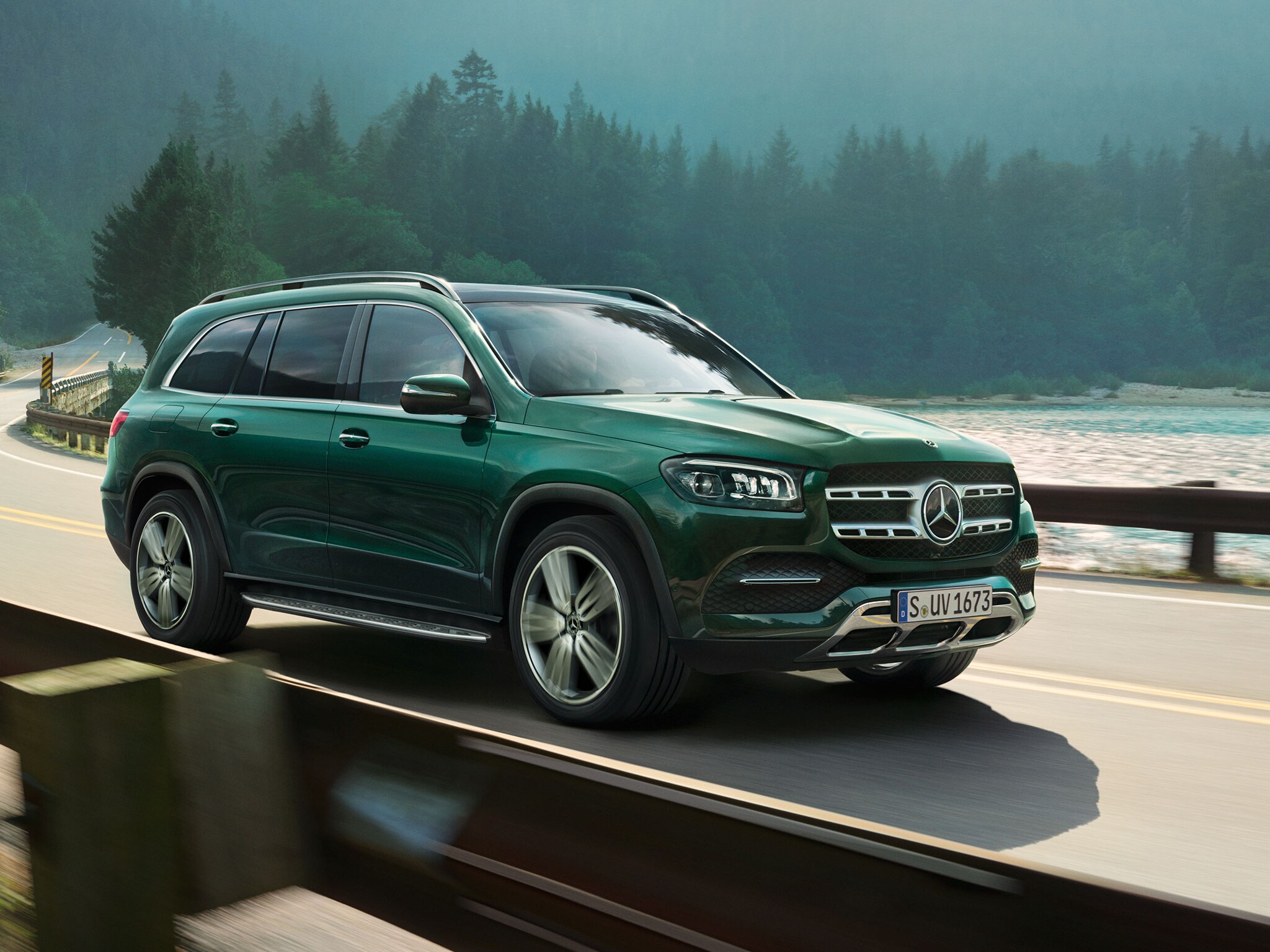 Ein grüner GLS fährt an einem See und Wäldern entlang.