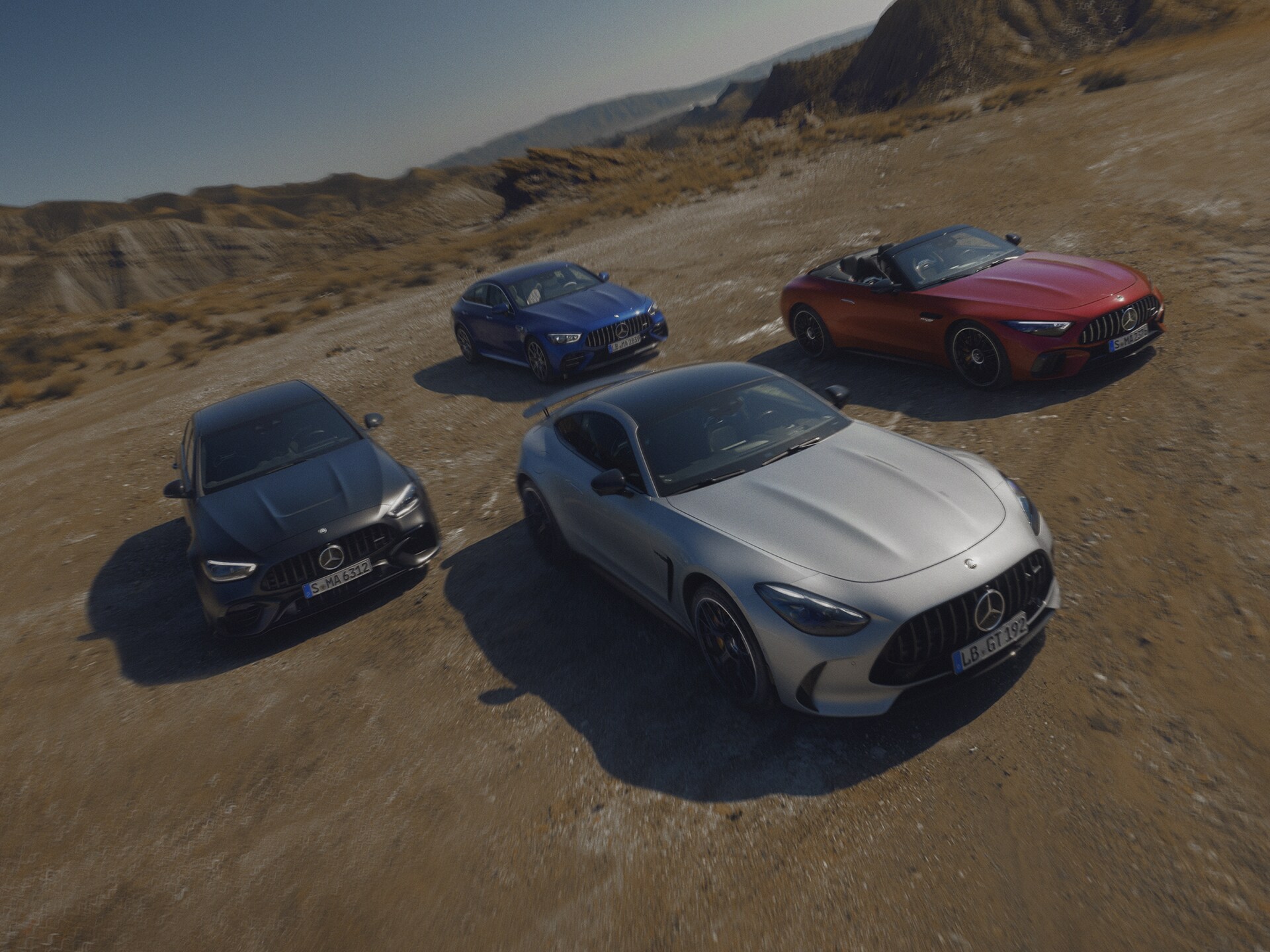 Vier unterschiedliche Mercedes-AMG Modelle parke in einer wüstenähnlichen Landschaft.