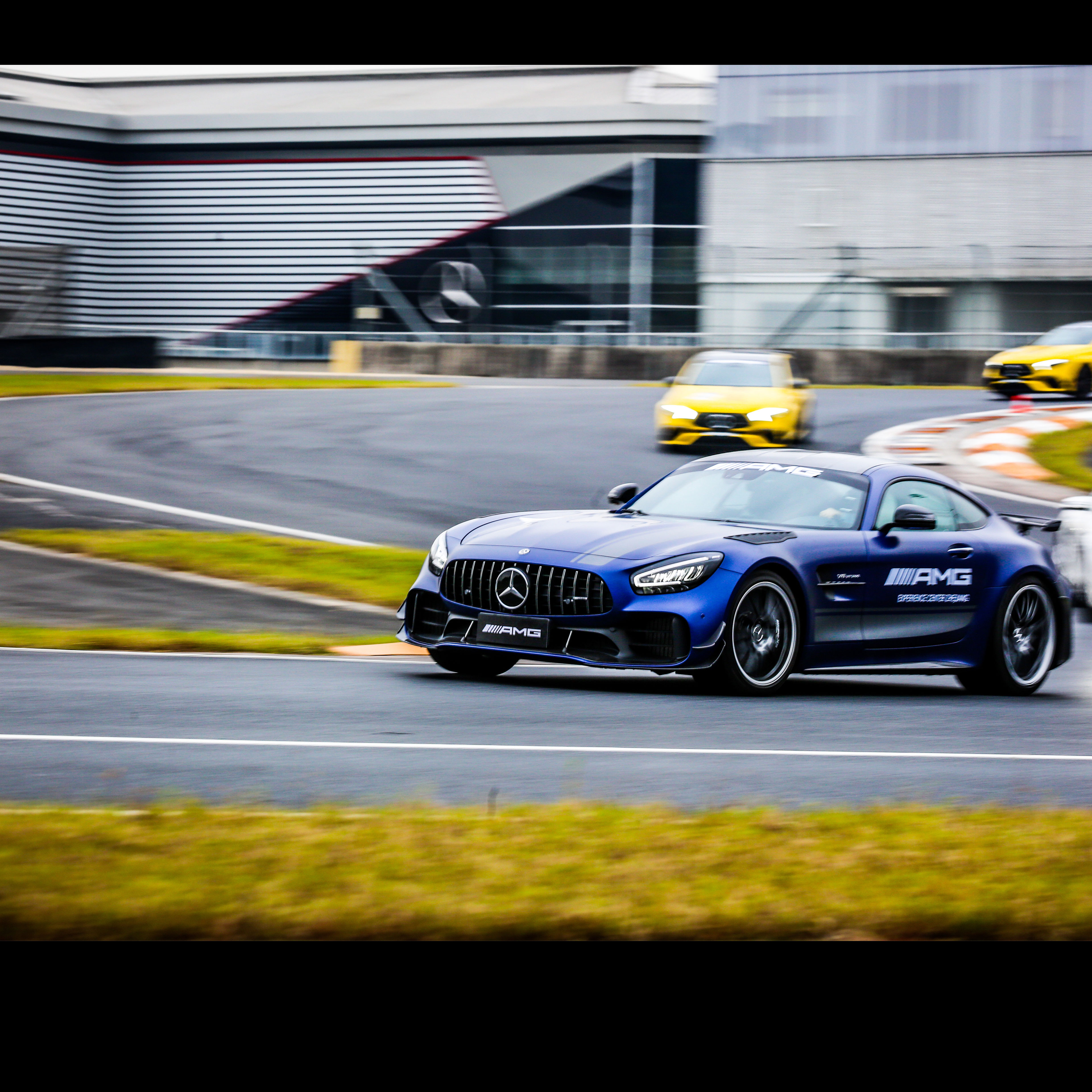 Die Welt von AMG | Mercedes-AMG Ein dunkelblauer Mercedes-AMG GT R fährt auf einer Rennstrecke und wird von zwei weiteren Autos verfolgt.