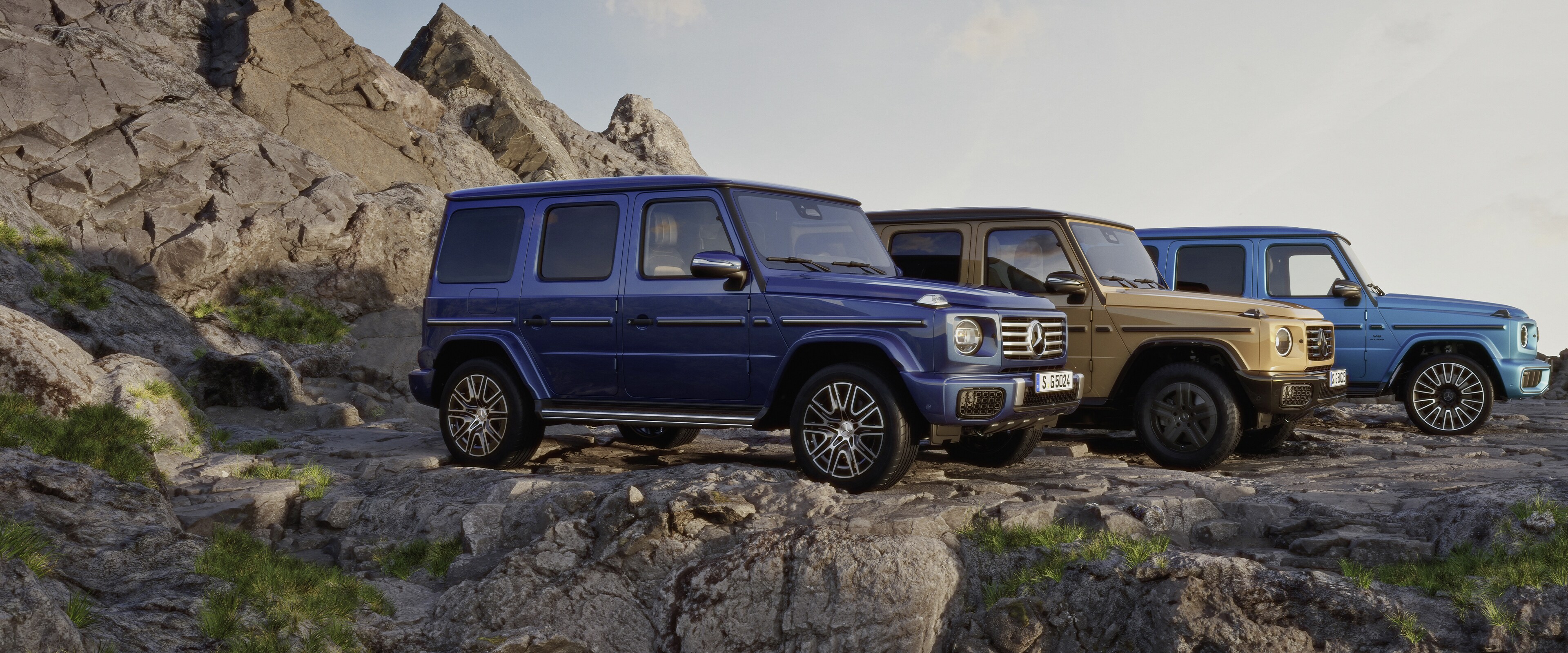Drei verschiedene Mercedes-Benz G-Klassen auf einem Berg.