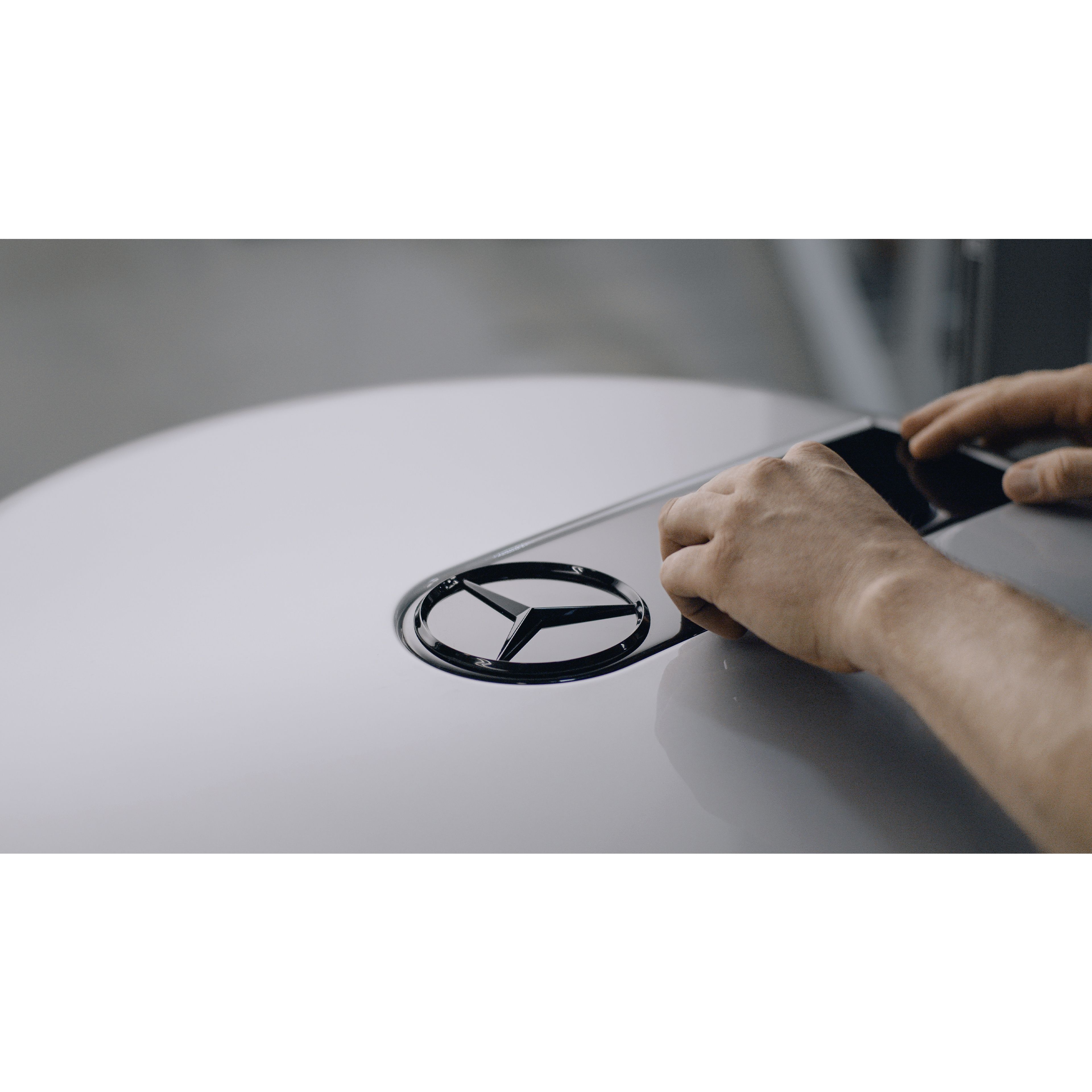 MANUFAKTUR | G-Klasse | Mercedes-Benz Ein schwarz glänzendes Mercedes-Benz Logo wird in den Radkasten von einer G-Klasse eingelassen.