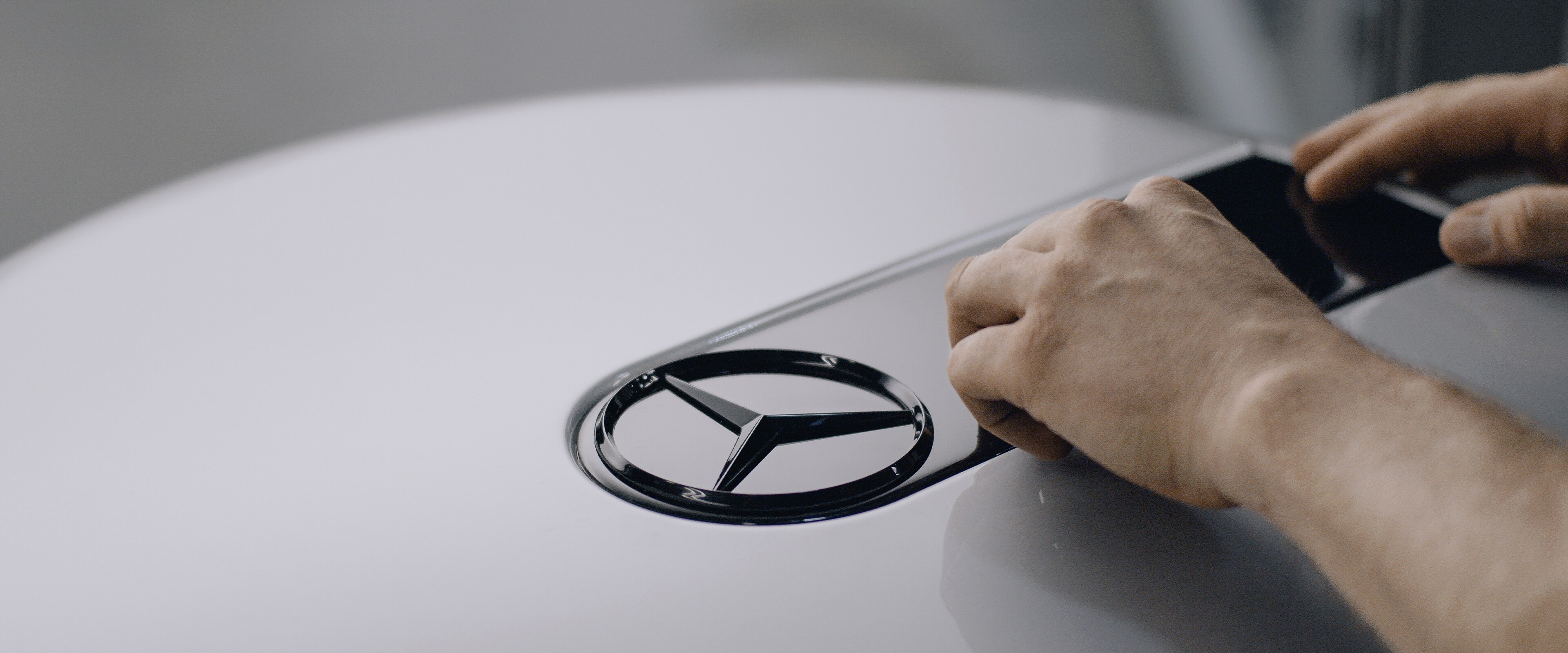 Ein schwarz glänzendes Mercedes-Benz Logo wird in den Radkasten von einer G-Klasse eingelassen.