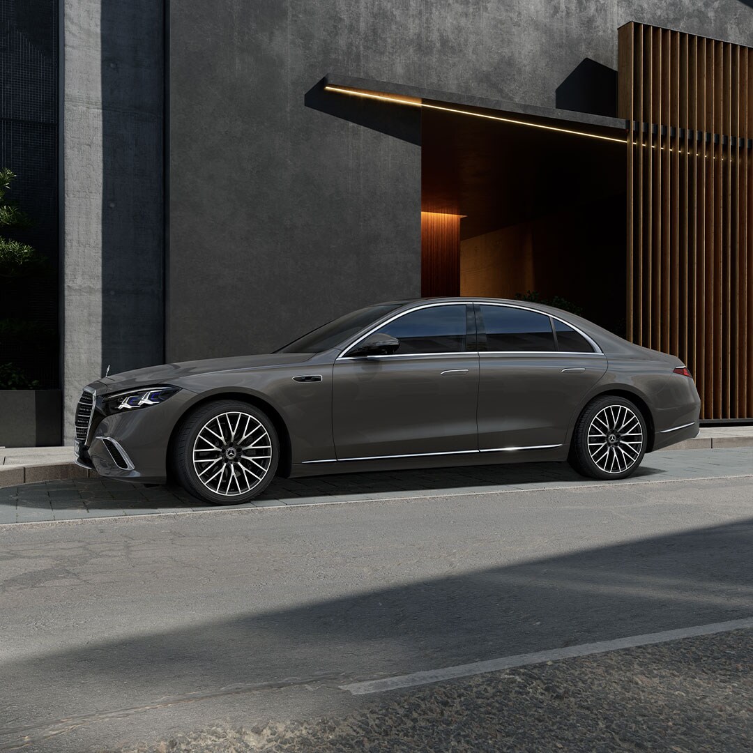 Die neue Mercedes-Benz S-Klasse in seitlicher Ansicht parkend vor einem modernem Gebäude.