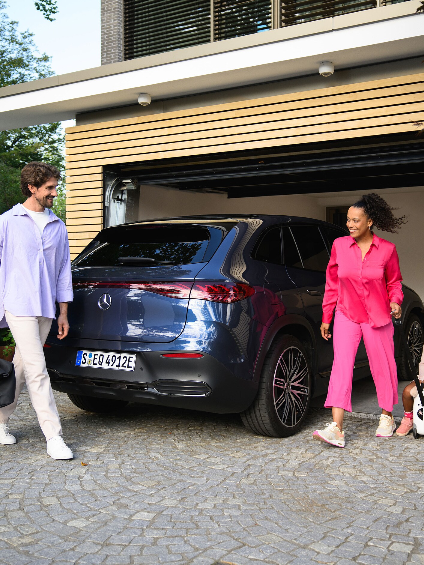 Zwei Erwachsene und ein Kind gehen zu ihrem Mercedes-Benz.