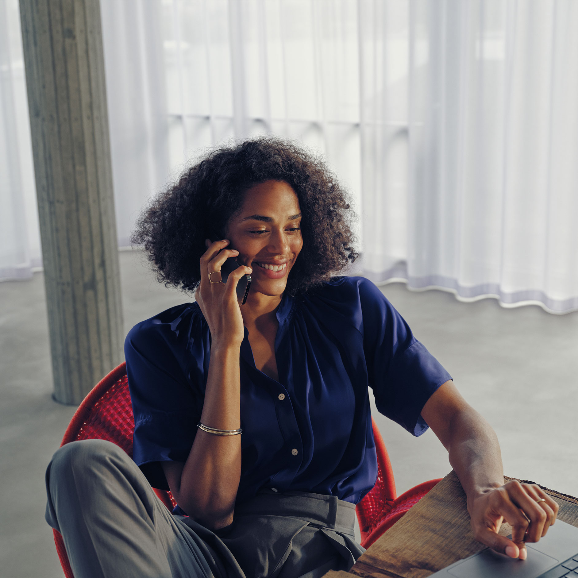 Fragen | Laden | Mercedes-Benz Eine Frau sitzt an einem Tisch und telefoniert.