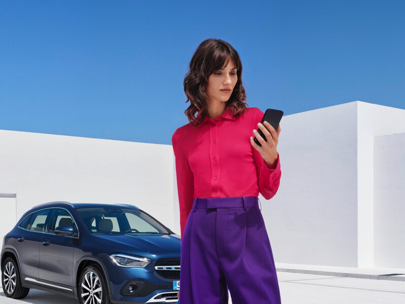 Eine Frau telefoniert vor ihrem Mercedes