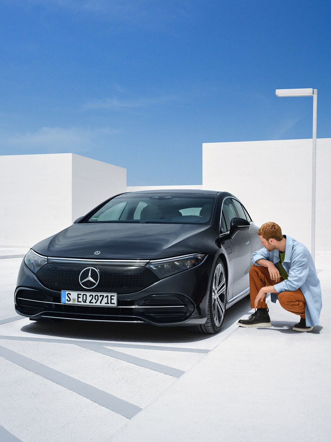 Ein Mann kniet neben seinem Mercedes-Benz, um ihn zu überprüfen