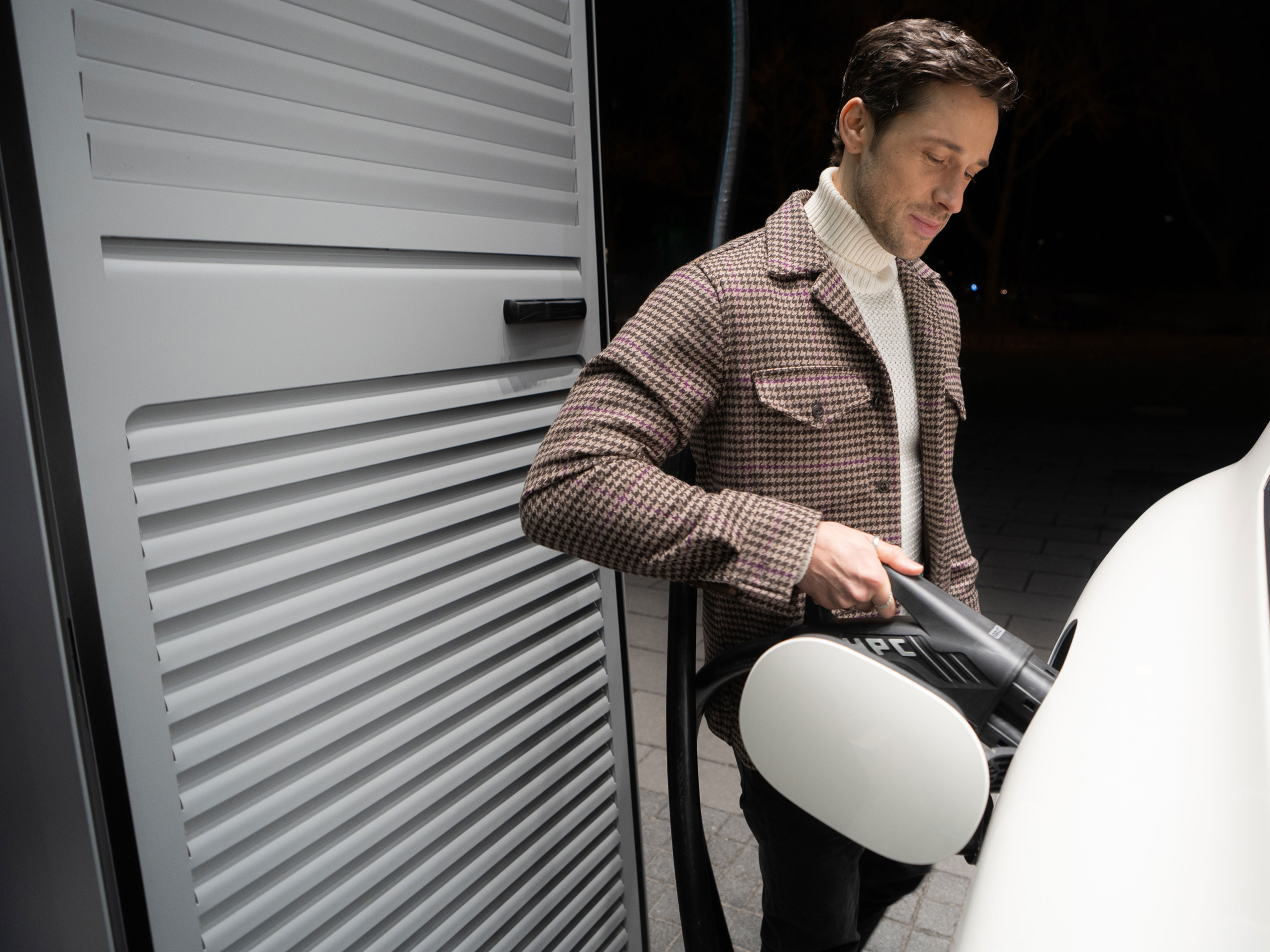 Öffentliches Laden | Ladelösungen für Geschäftskunden | Mercedes-Benz. Ein Mann lädt unterwegs sein Mercedes-Benz Elektroauto an einer Ladesäule mit MB.CHARGE Public.