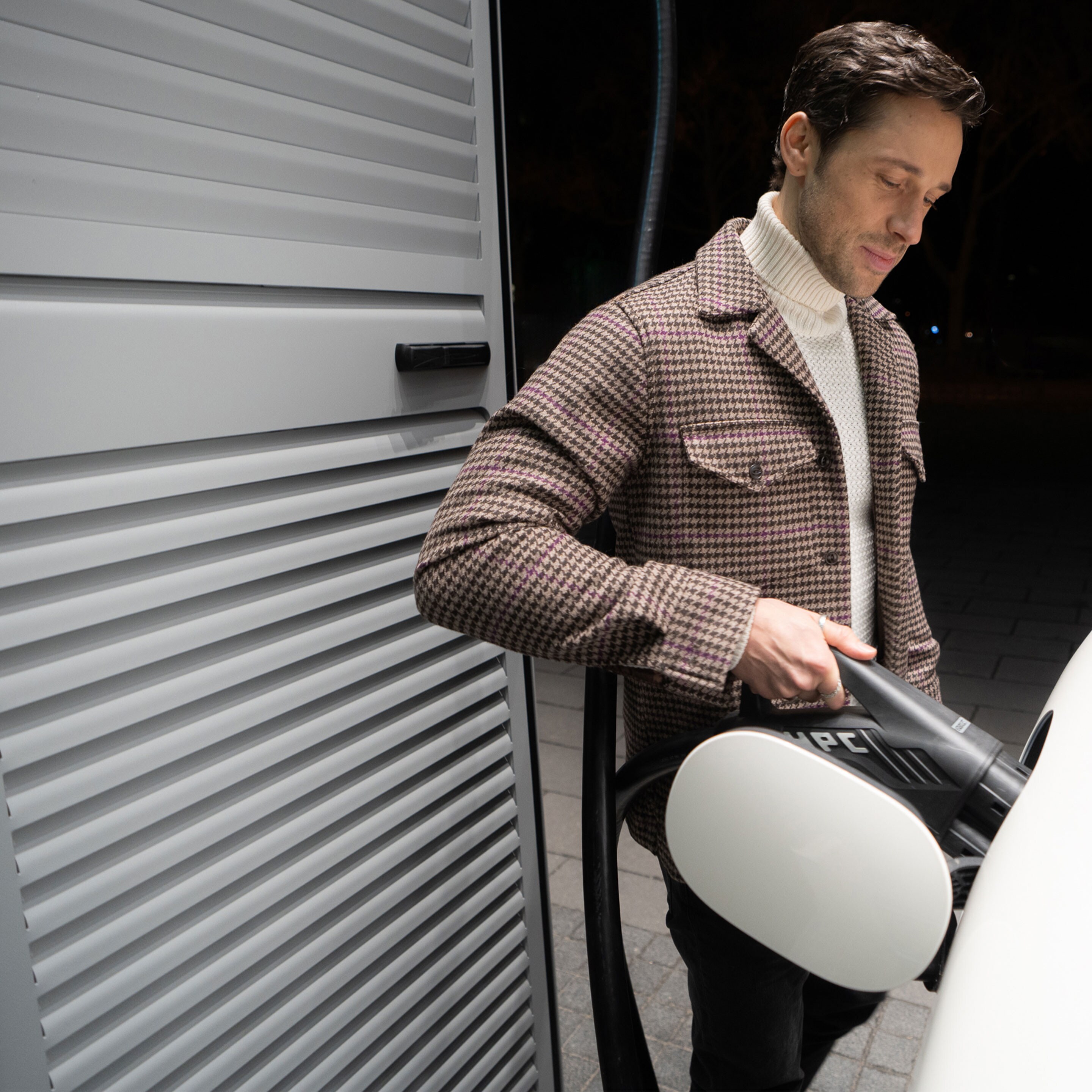 Ein Mann lädt unterwegs sein Mercedes-Benz Elektroauto an einer Ladesäule mit MB.CHARGE Public.
