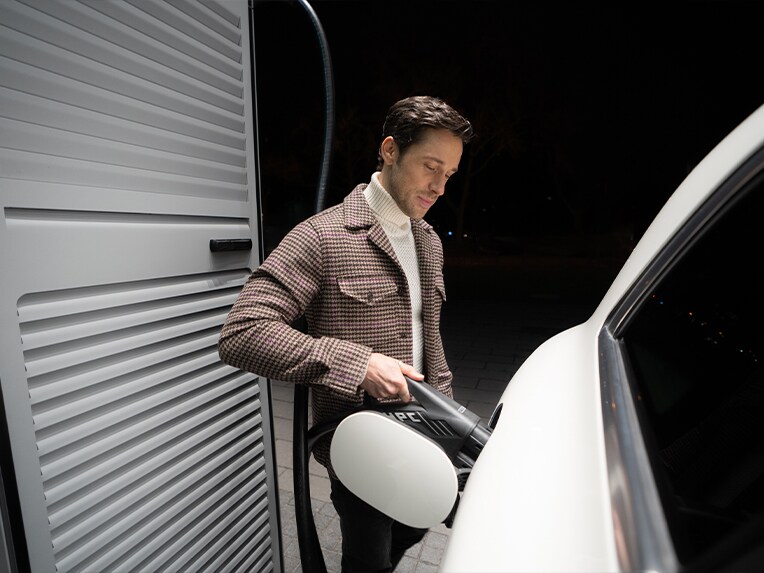 Ein Mann lädt sein Mercedes-Benz Elektroauto an einer Ladestation.