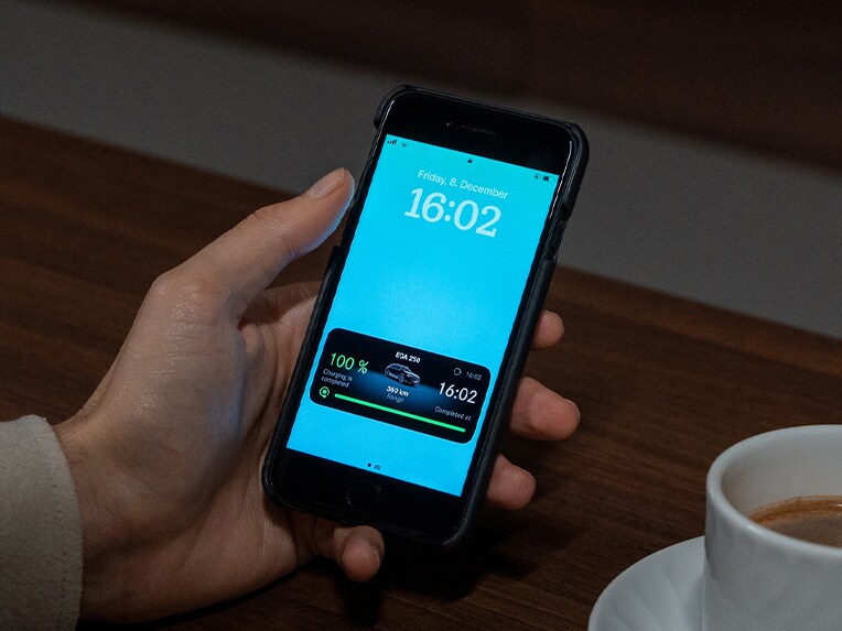Ein Mann hält ein Smartphone mit der Mercedes-Benz App in der Hand.
